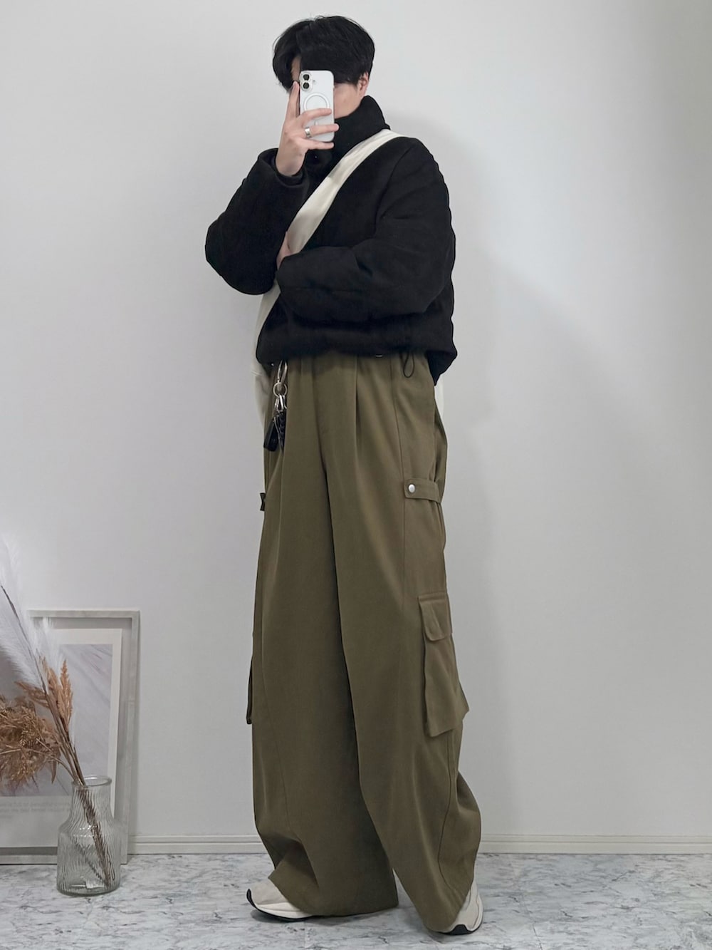 ベージュ系のショルダーバッグ、ブラック系のダウンジャケット/コート、グリーン系のカーゴパンツを着用したメンズの冬コーディネートの2枚目の写真