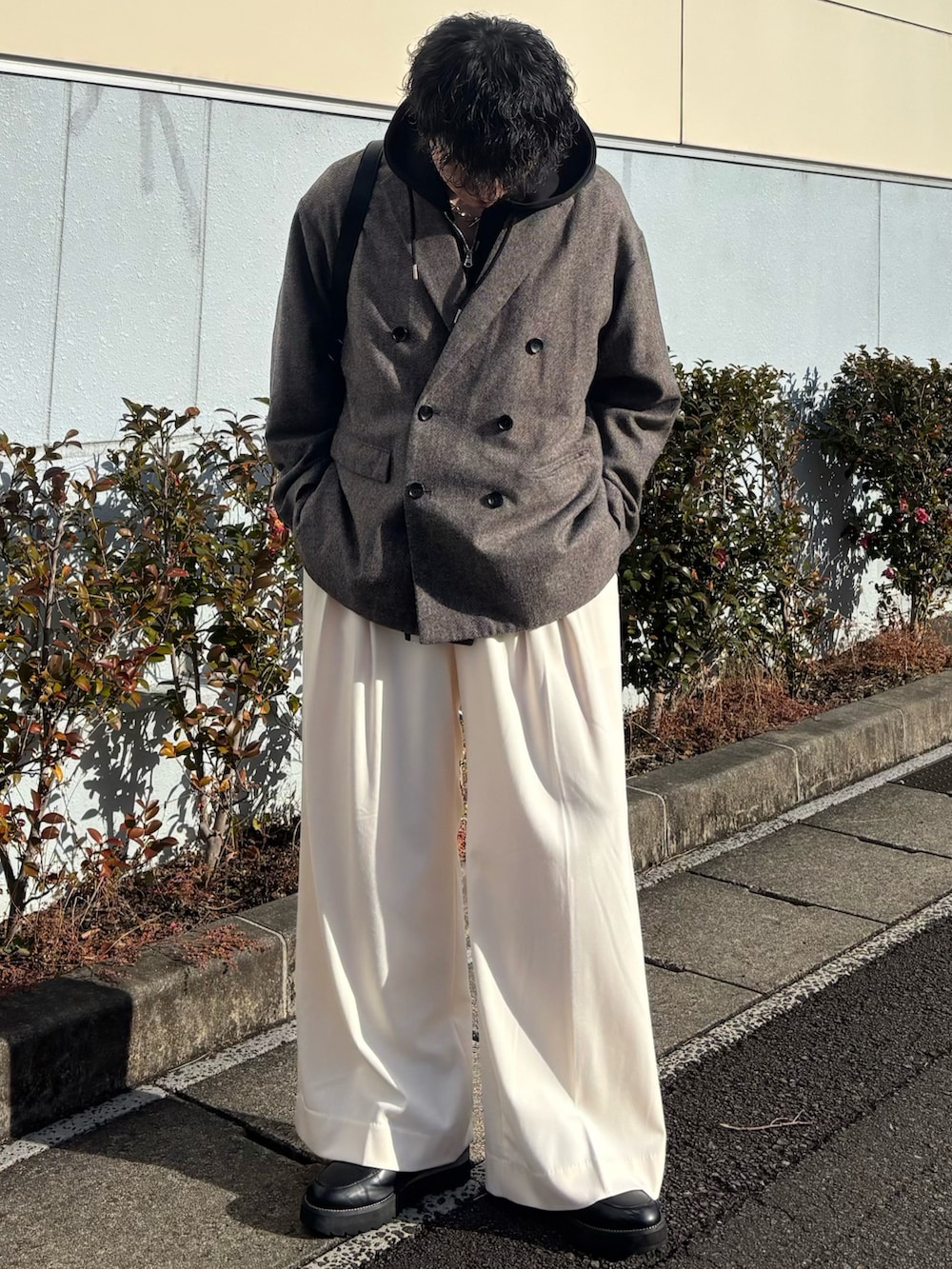 ブラック系のパーカー、グレー系のテーラードジャケット、ホワイト系のスラックスを着用したメンズの春コーディネートの2枚目の写真