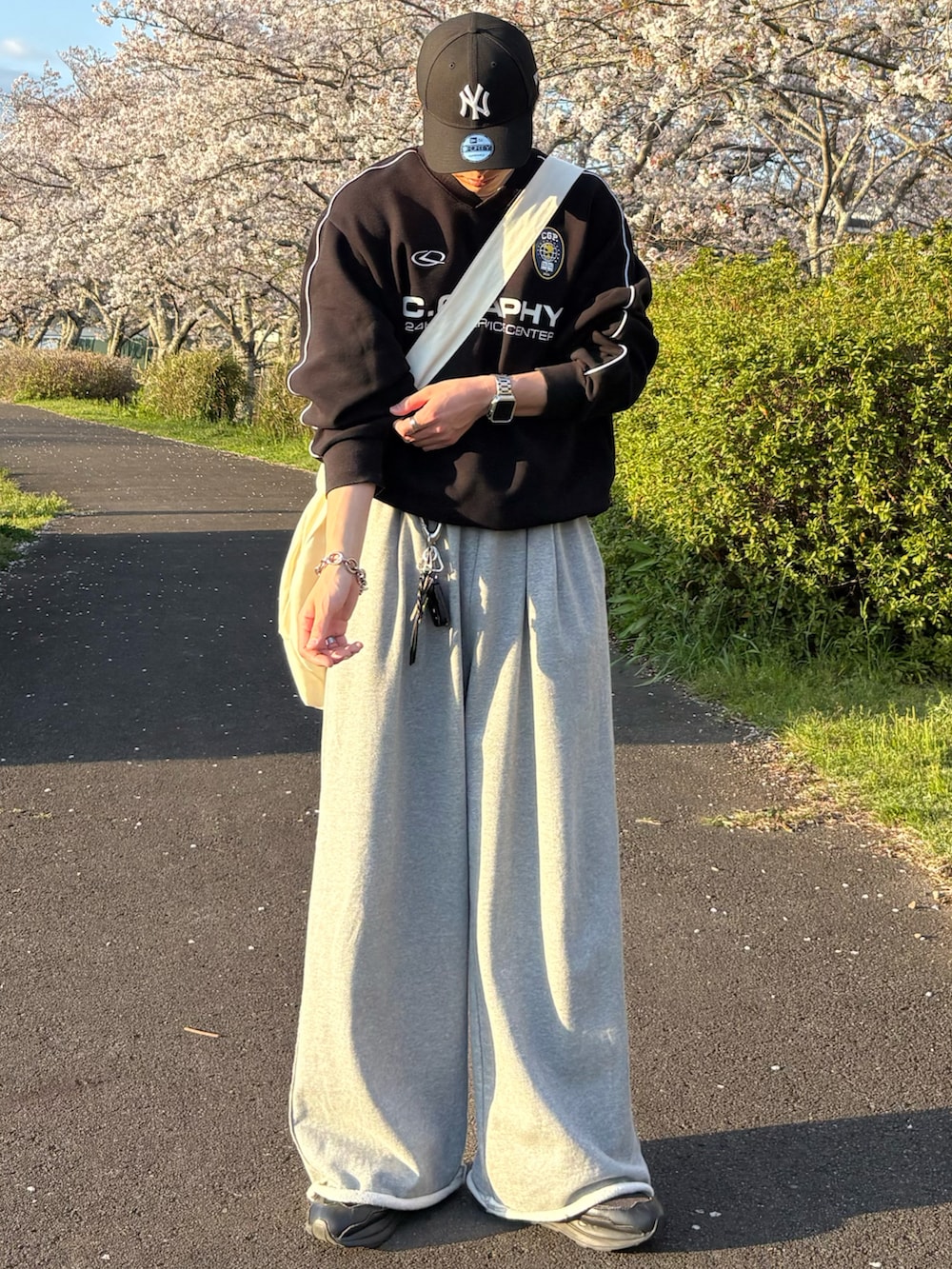 ブラック系のスウェット、グレー系のスウェットパンツ、ベージュ系のショルダーバッグを着用したメンズの春コーディネートの2枚目の写真
