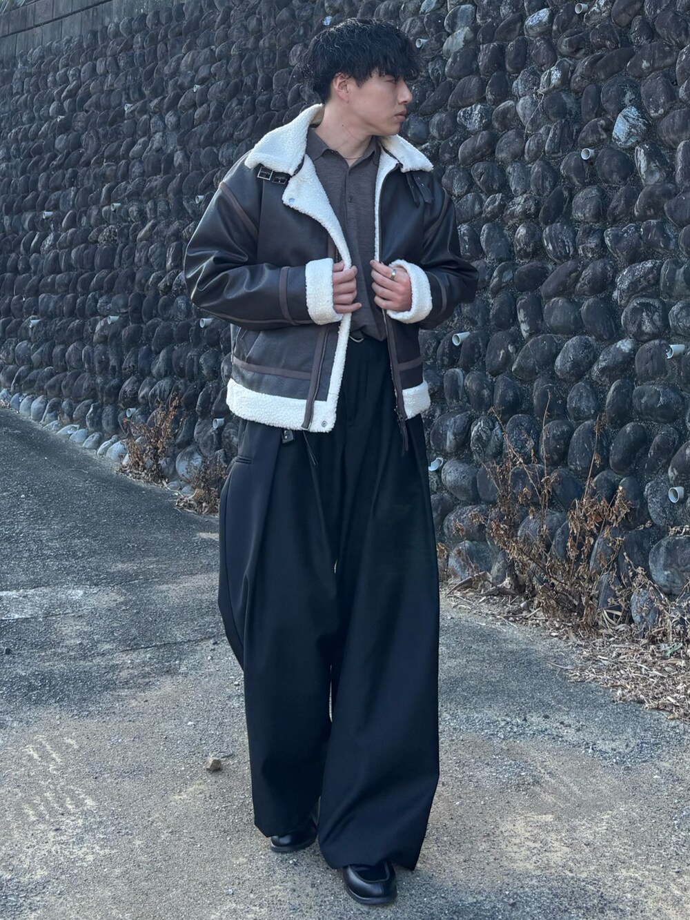 ブラウン系のブルゾン、ブラック系のローファー、ブラウン系のポロシャツを着用したメンズの冬コーディネートの2枚目の写真