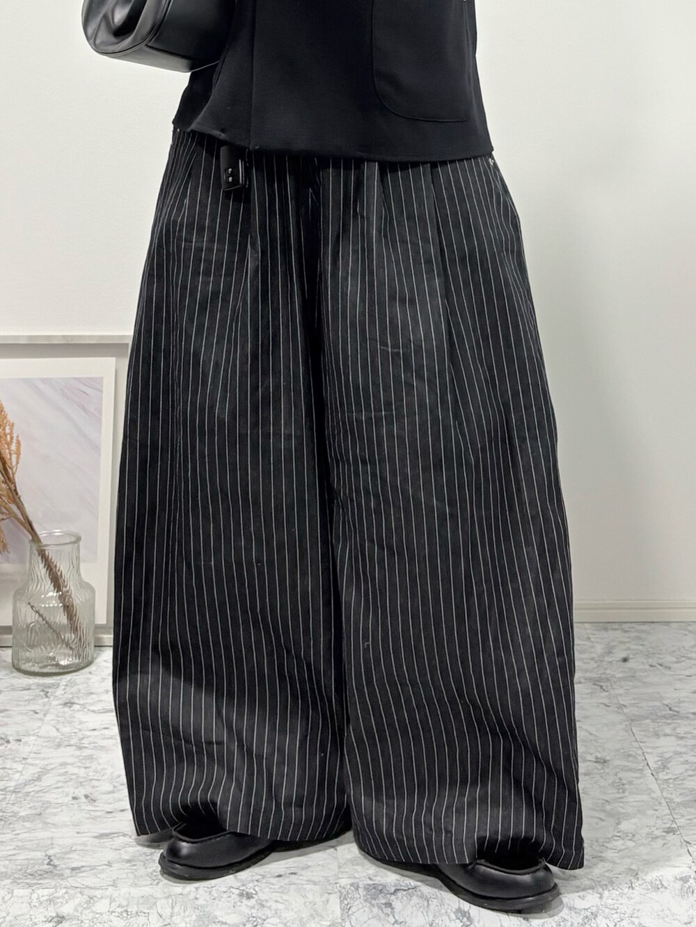 その他のスラックス、ブラック系のローファー、ブラック系のハンドバッグを着用したメンズの冬コーディネートの3枚目の写真