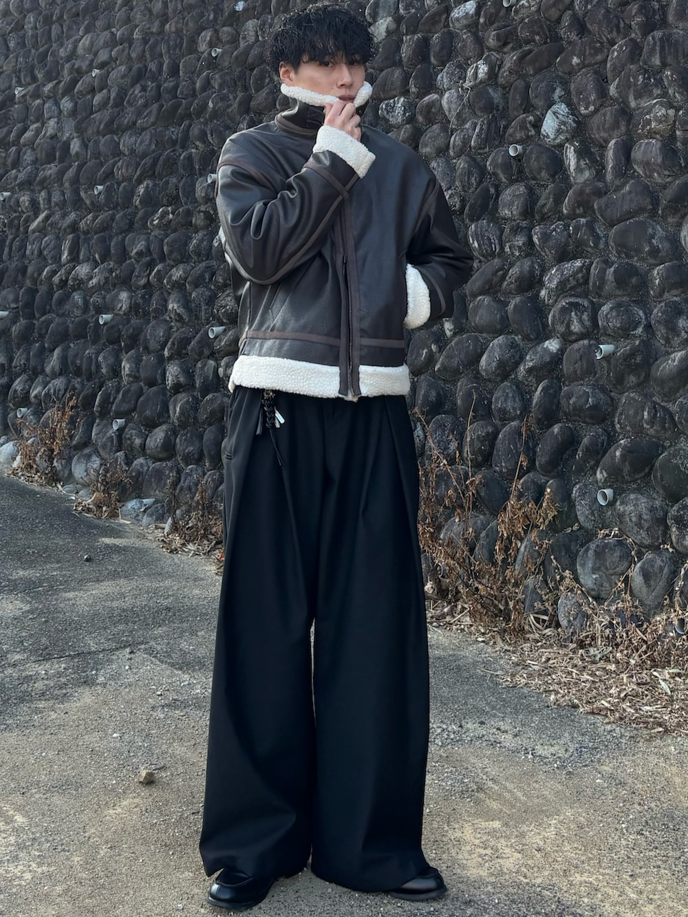 ブラウン系のブルゾン、ブラック系のローファー、ブラウン系のポロシャツを着用したメンズの冬コーディネートの3枚目の写真