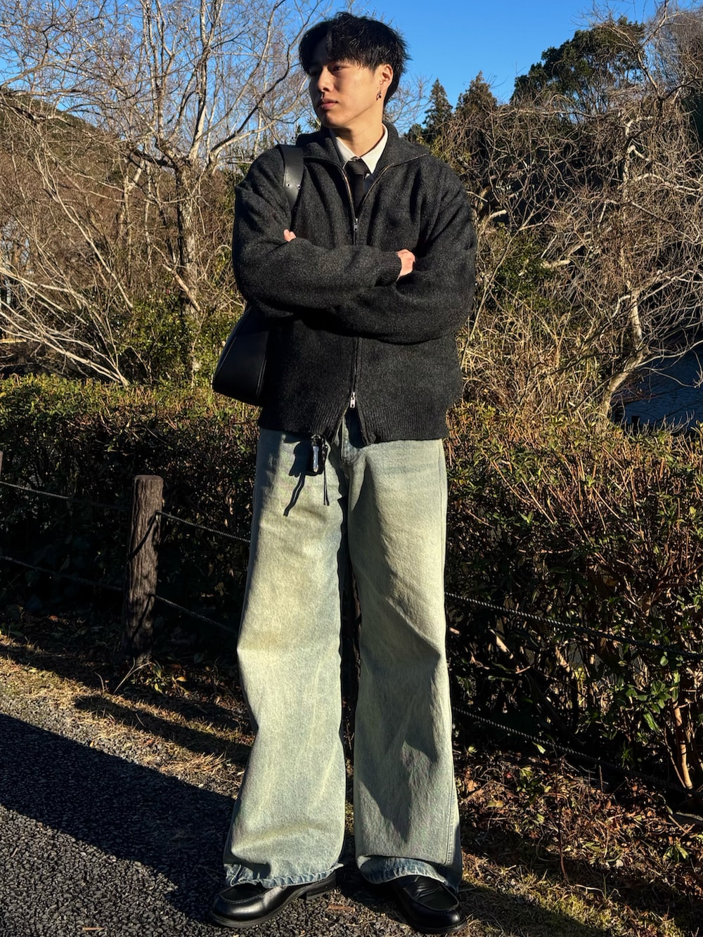 ブラック系のローファー、グレー系のニット/セーター、ブルー系のデニムパンツを着用したメンズの春コーディネートの3枚目の写真