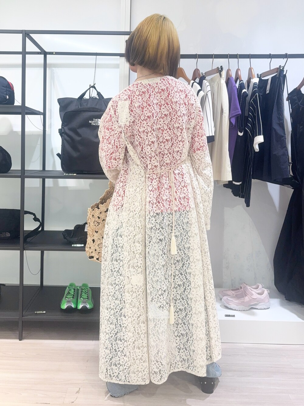 ホワイト系のワンピース、ブルー系のデニムパンツ、ベージュ系のショルダーバッグを着用したレディースの春コーディネートの4枚目の写真
