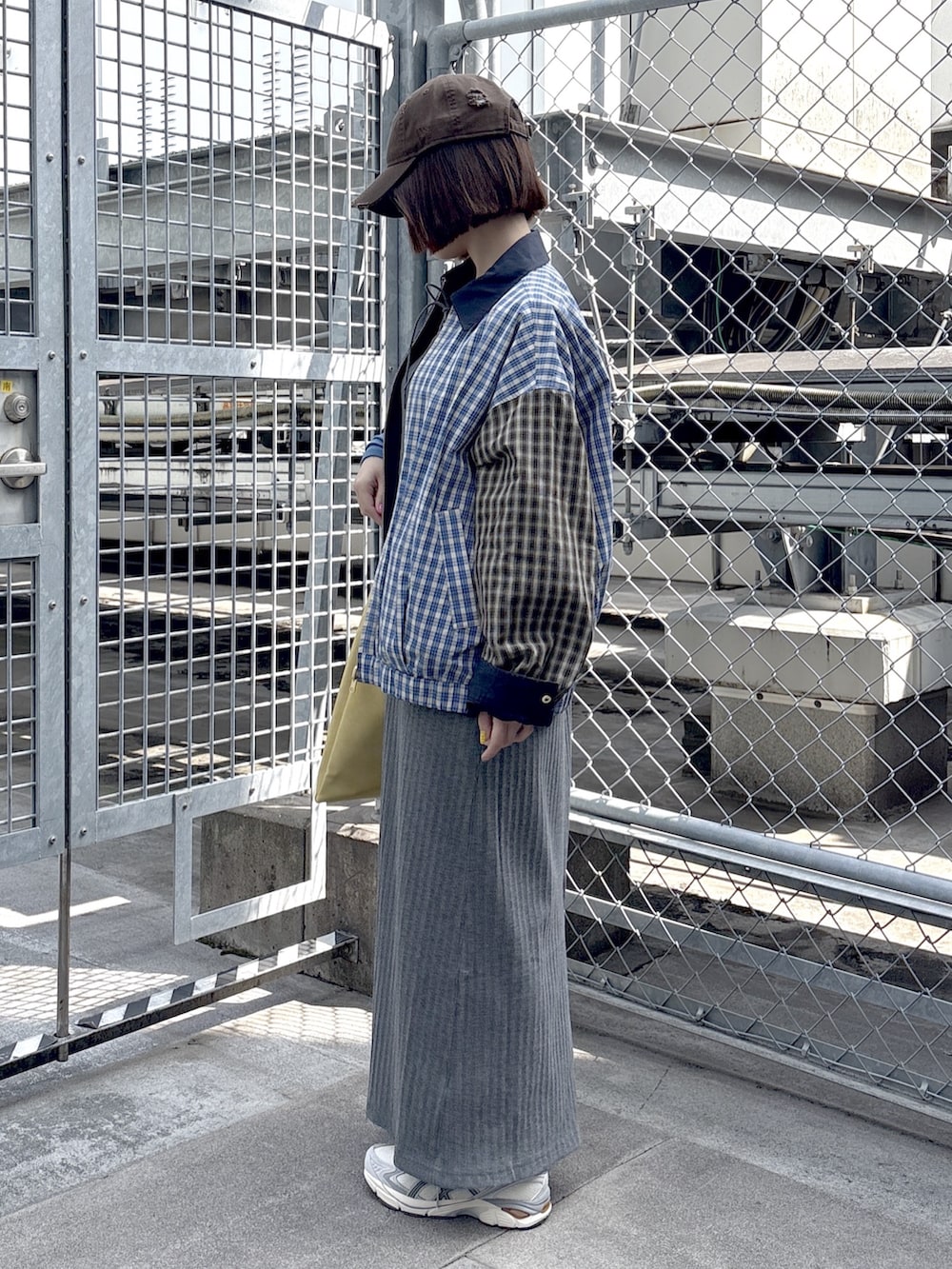 グレー系のワンピース、ブルー系のブルゾン、ホワイト系のスニーカーを着用したレディースの春コーディネートの2枚目の写真