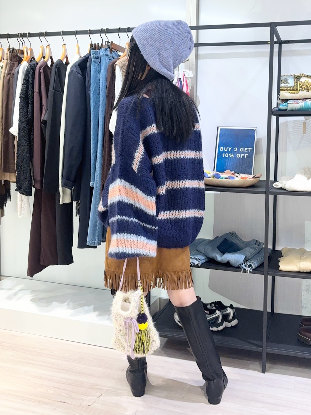 ブルー系のニット/セーター、ホワイト系のショルダーバッグ、ブラウン系のスカートを着用したレディースの秋コーディネートの4枚目の写真