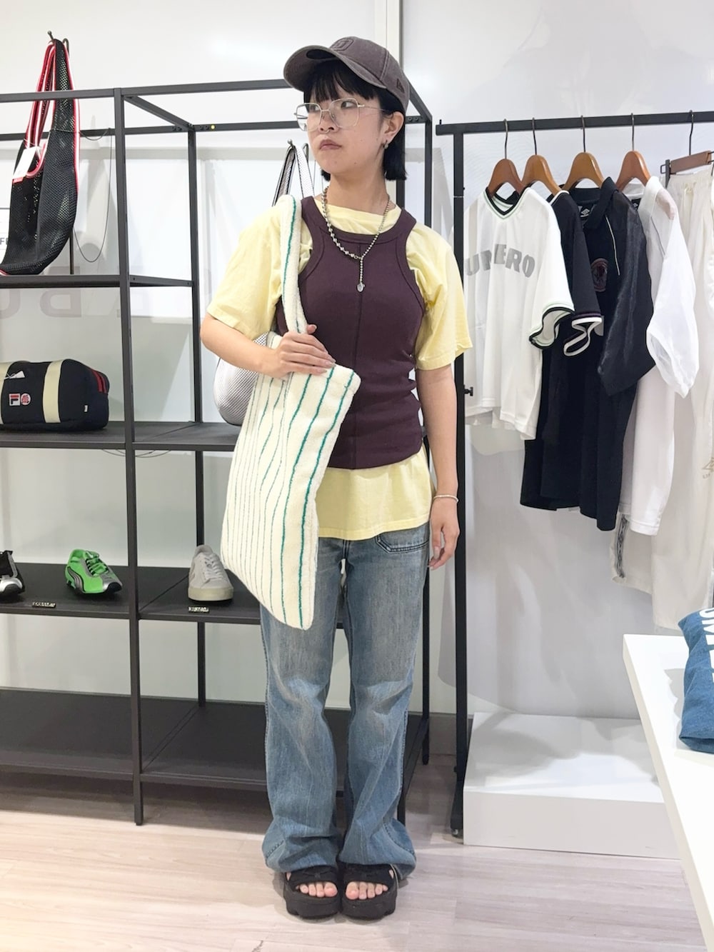 ブルー系のデニムパンツ、ブラック系のサンダル、イエロー系のTシャツ/カットソーを着用したレディースの夏コーディネートの2枚目の写真