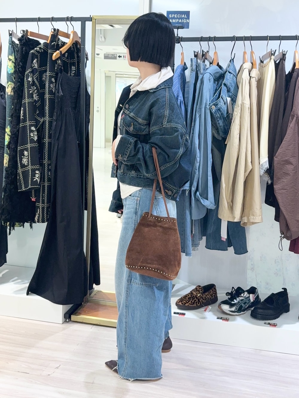ベージュ系のTシャツ/カットソー、ブルー系のデニムパンツ、ブラウン系のショルダーバッグを着用したレディースの秋コーディネートの3枚目の写真