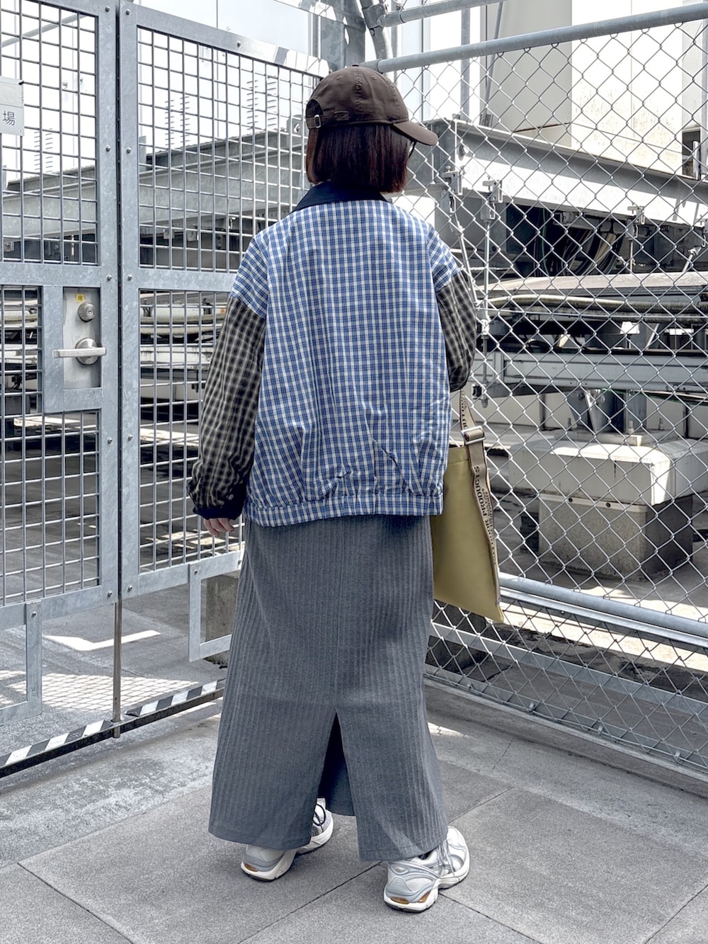 グレー系のワンピース、ブルー系のブルゾン、ホワイト系のスニーカーを着用したレディースの春コーディネートの3枚目の写真