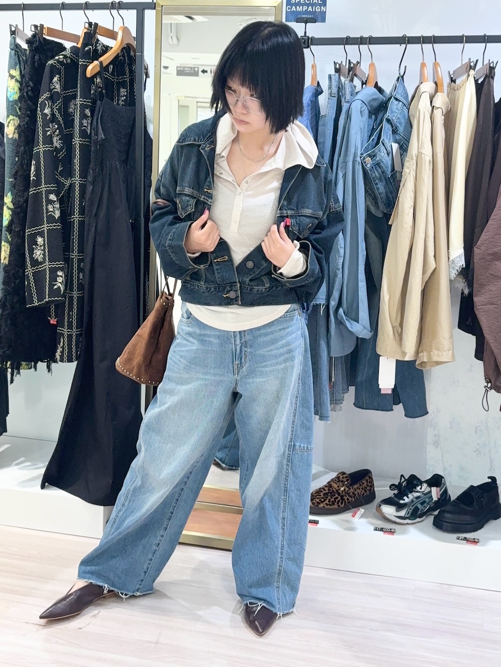 ベージュ系のTシャツ/カットソー、ブルー系のデニムパンツ、ブラウン系のショルダーバッグを着用したレディースの秋コーディネートの2枚目の写真