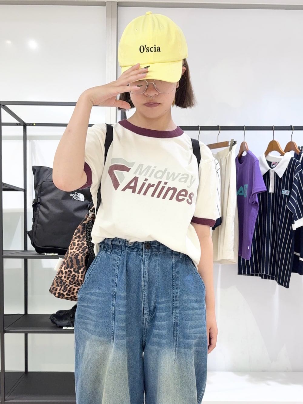 ブラウン系のトートバッグ、ブルー系のデニムパンツ、ブラック系のスニーカーを着用したレディースの夏コーディネートの5枚目の写真