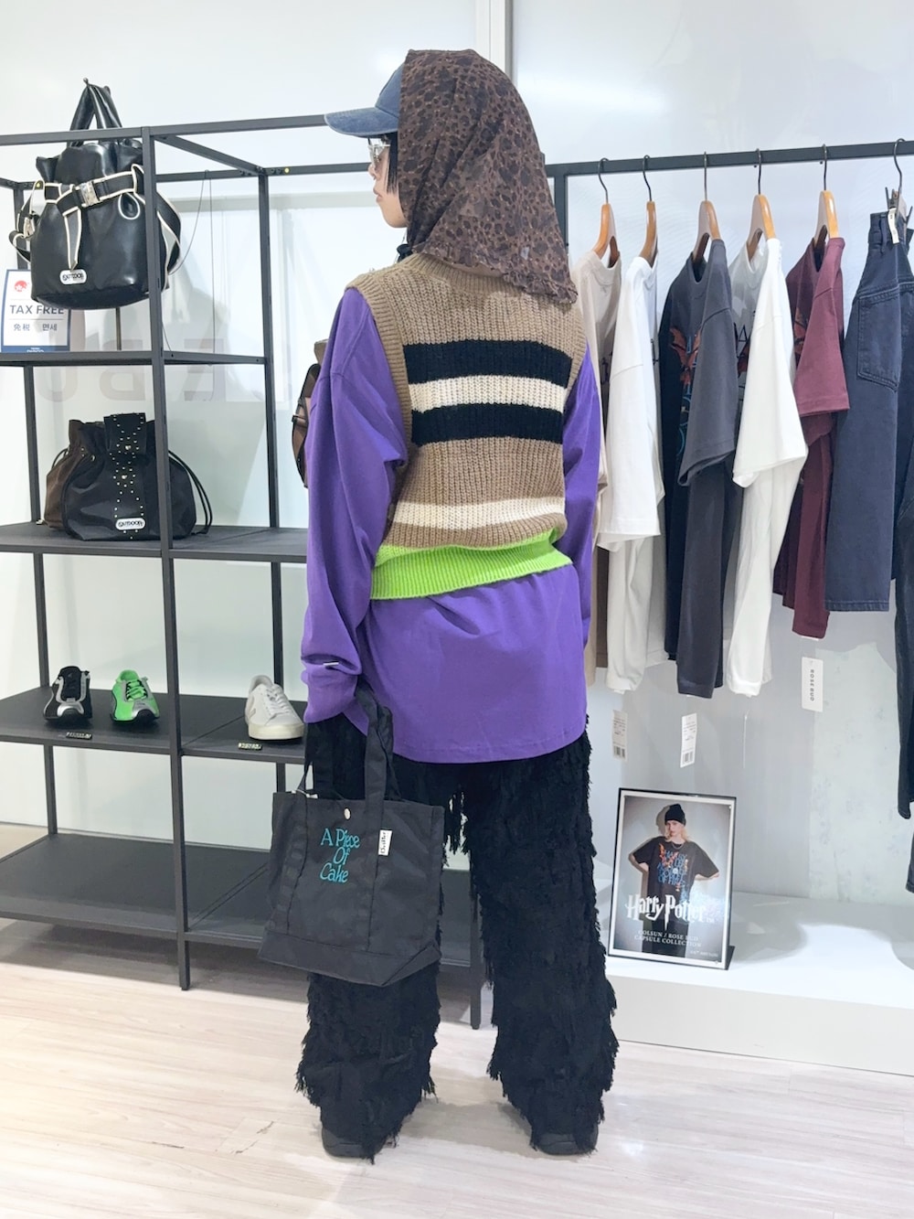 ブラック系のトートバッグ、パープル系のTシャツ/カットソー、ベージュ系のベストを着用したレディースの秋コーディネートの4枚目の写真