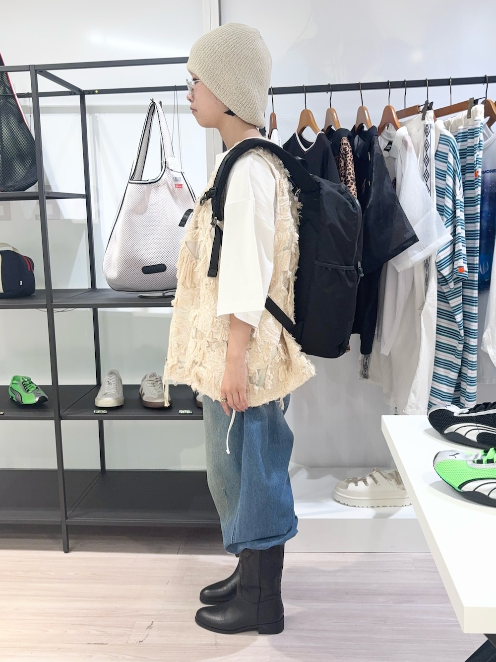 ベージュ系のベスト、ブラック系のバックパック/リュック、ブルー系のデニムパンツを着用したレディースの夏コーディネートの3枚目の写真