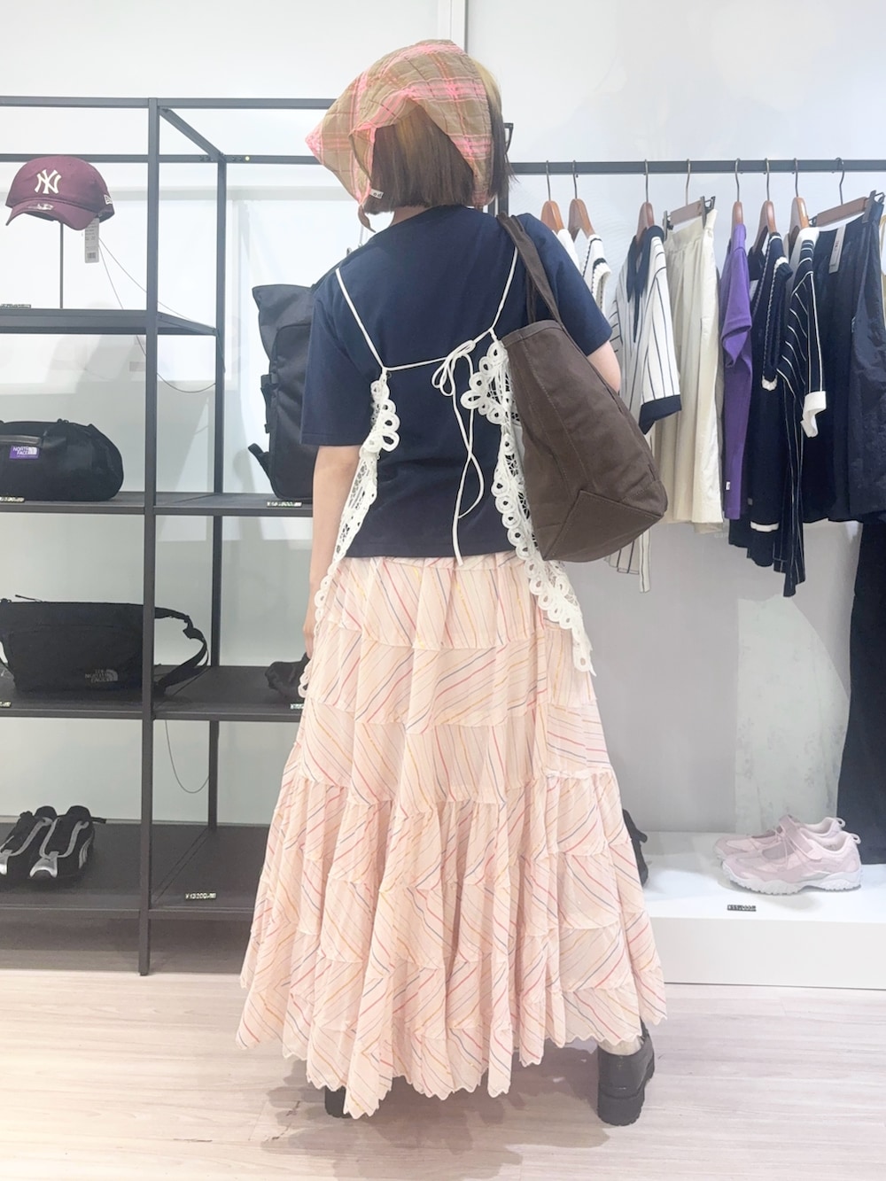 ブラウン系のトートバッグ、ホワイト系のキャミソール、ブルー系のTシャツ/カットソーを着用したレディースの春コーディネートの4枚目の写真