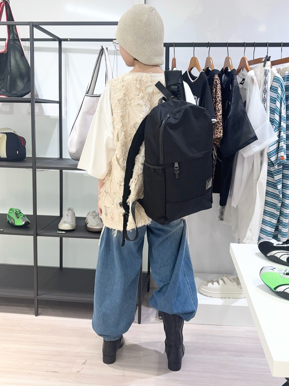 ベージュ系のベスト、ブラック系のバックパック/リュック、ブルー系のデニムパンツを着用したレディースの夏コーディネートの4枚目の写真