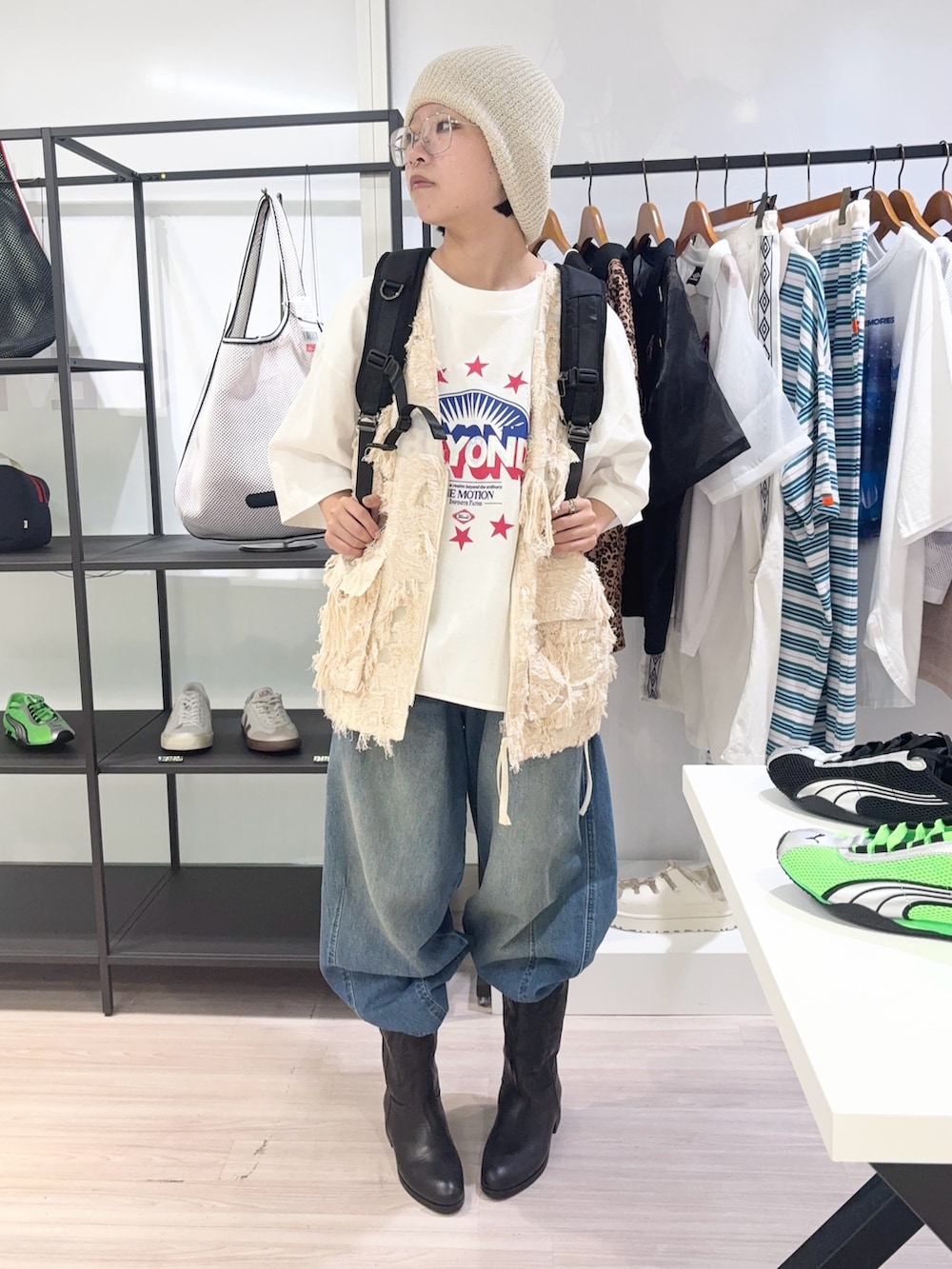 ベージュ系のベスト、ブラック系のバックパック/リュック、ブルー系のデニムパンツを着用したレディースの夏コーディネートの2枚目の写真