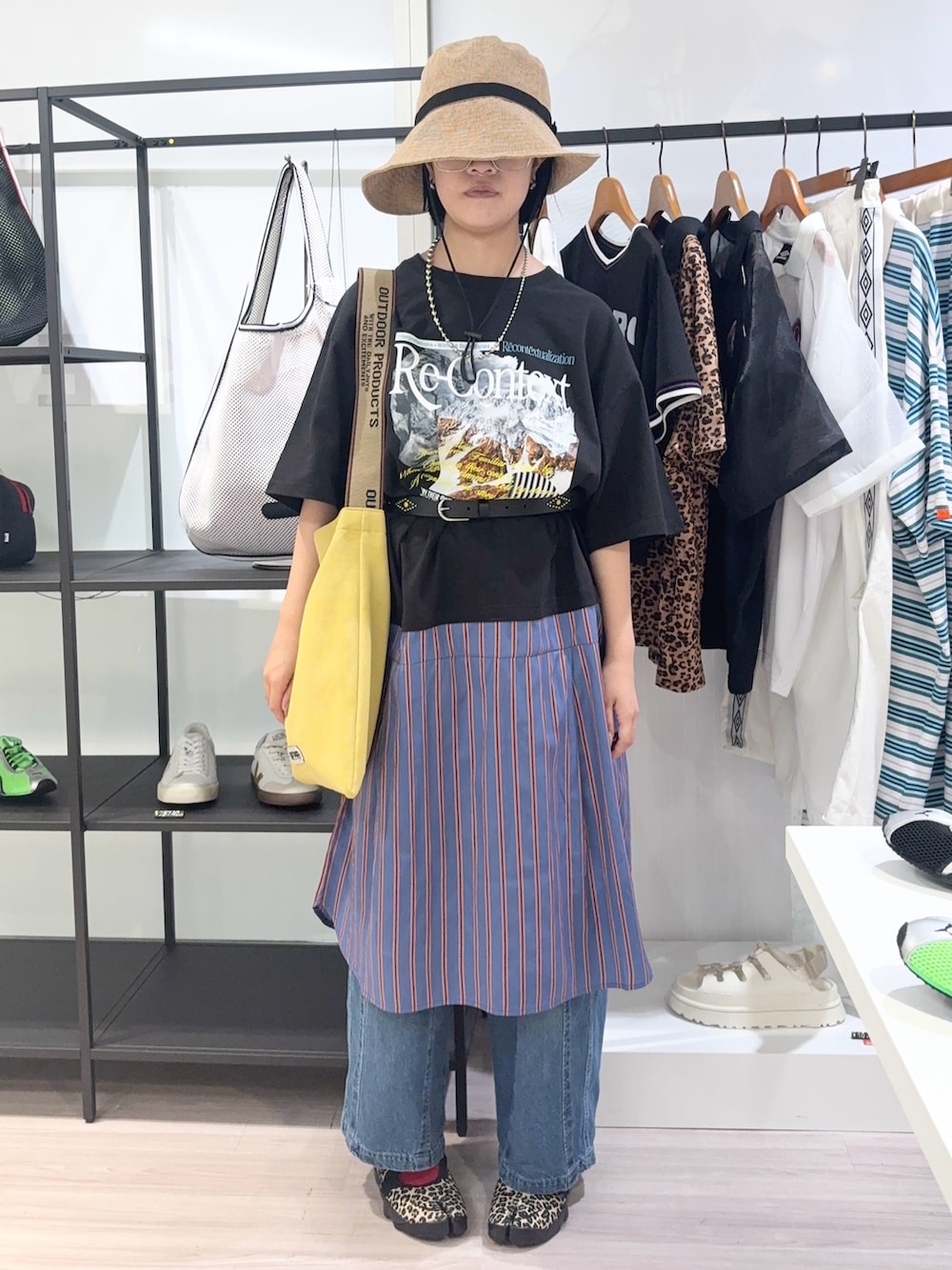 ブルー系のデニムパンツ、ブラック系のスニーカー、イエロー系のトートバッグを着用したレディースの夏コーディネートの2枚目の写真