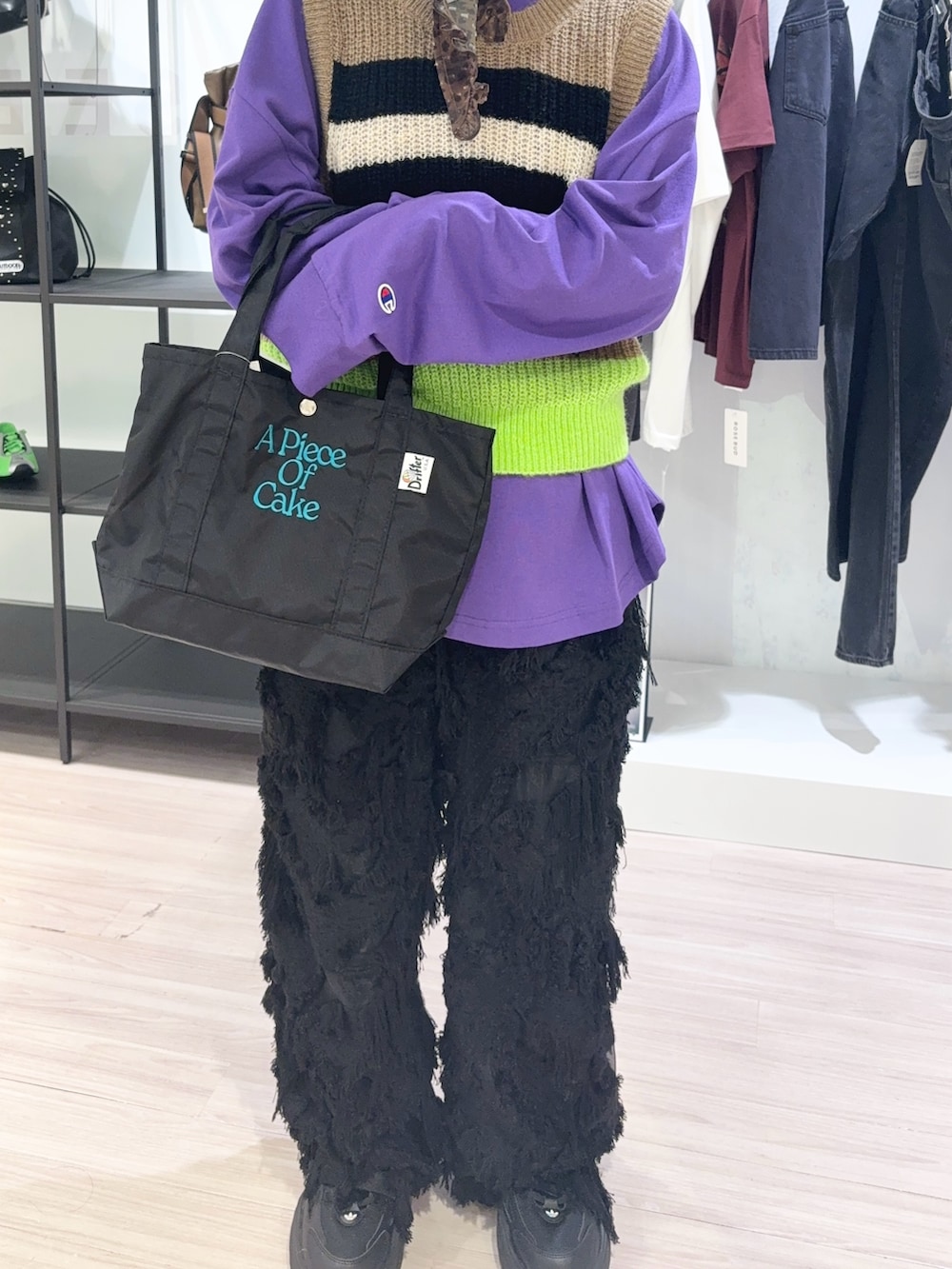 ブラック系のトートバッグ、パープル系のTシャツ/カットソー、ベージュ系のベストを着用したレディースの秋コーディネートの5枚目の写真