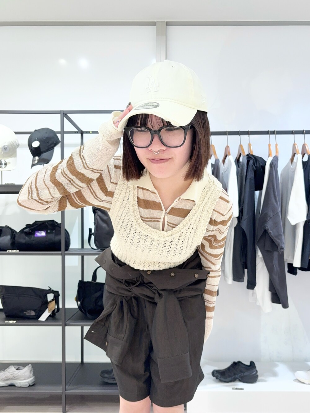 ホワイト系のトートバッグ、ホワイト系のカーディガン/ボレロ、ブラック系のつなぎ/オールインワンを着用したレディースの春コーディネートの6枚目の写真