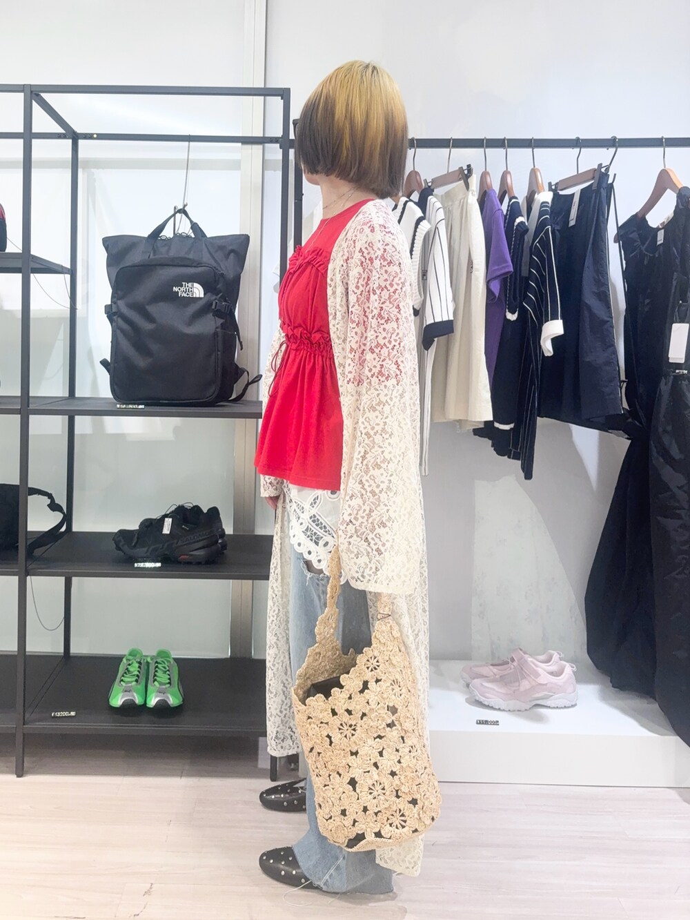 ホワイト系のワンピース、ブルー系のデニムパンツ、ベージュ系のショルダーバッグを着用したレディースの春コーディネートの3枚目の写真