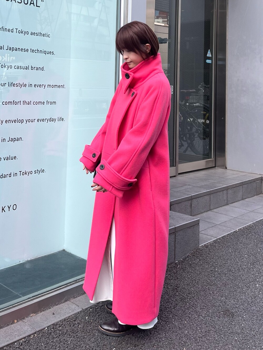 ピンク系のステンカラーコートを着用したレディースの冬コーディネートの2枚目の写真