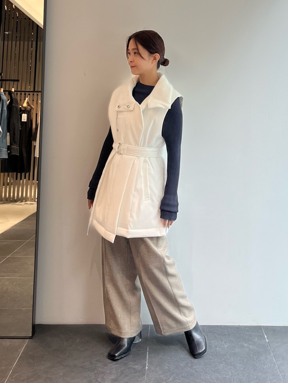 グレー系のニット/セーター、ベージュ系のダウンベスト、その他のスラックスを着用したレディースの秋コーディネートの2枚目の写真