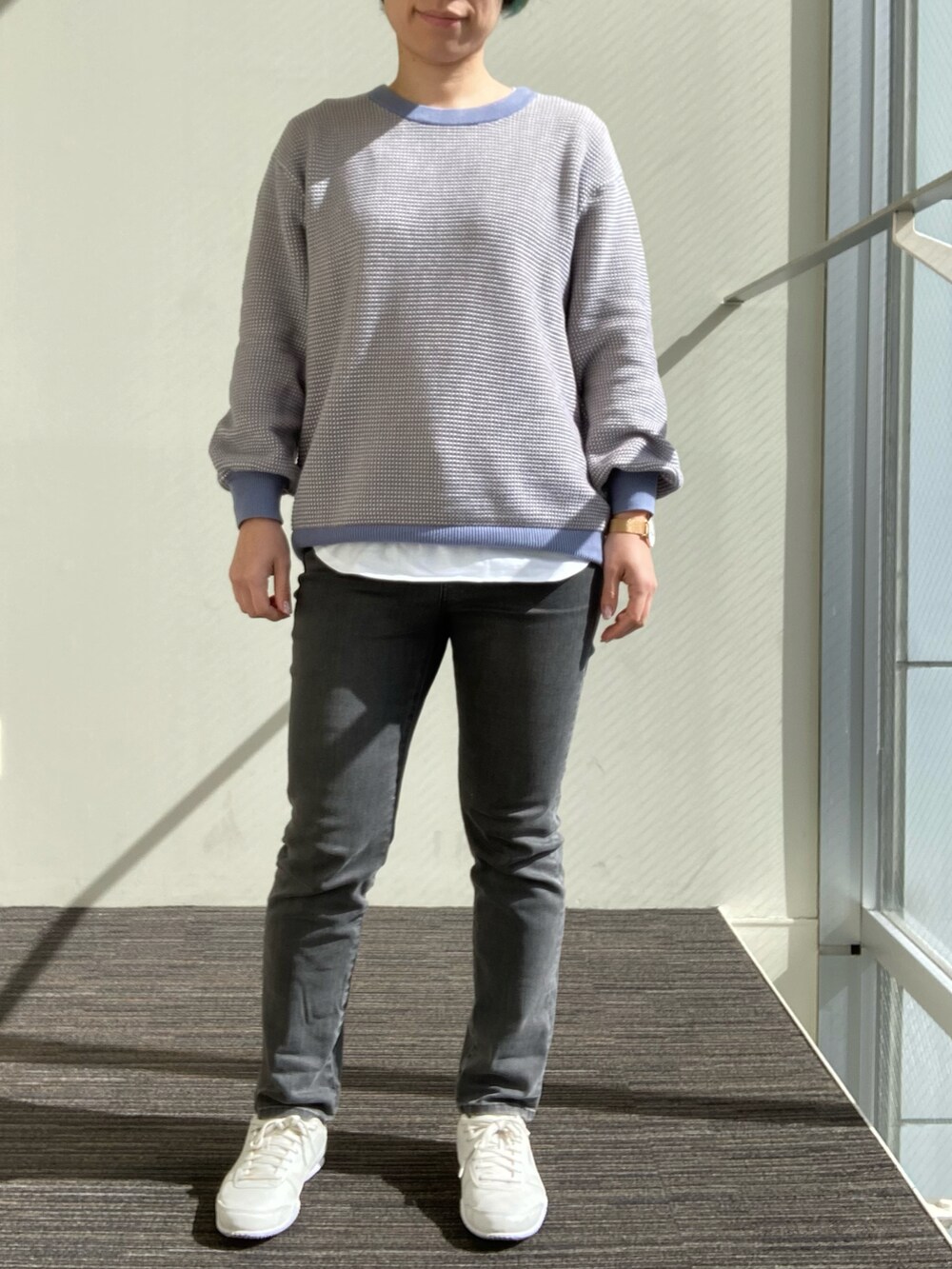 ブルー系のニット/セーター、ホワイト系のTシャツ/カットソー、グレー系のデニムパンツを着用したレディースの冬コーディネートの2枚目の写真