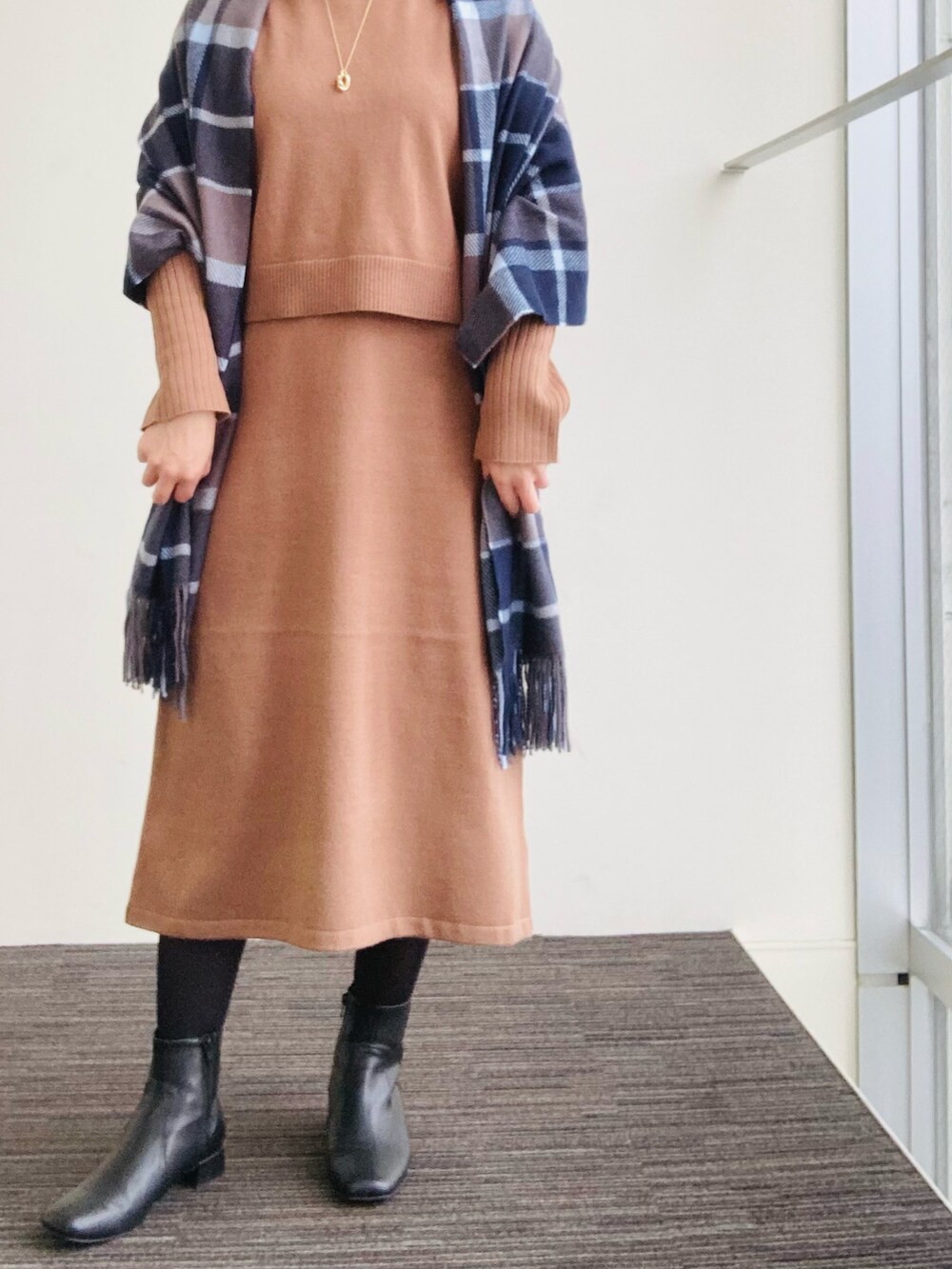 ブラウン系のワンピース、ブラック系のブーツ、ブルー系のマフラーを着用したレディースの冬コーディネートの2枚目の写真