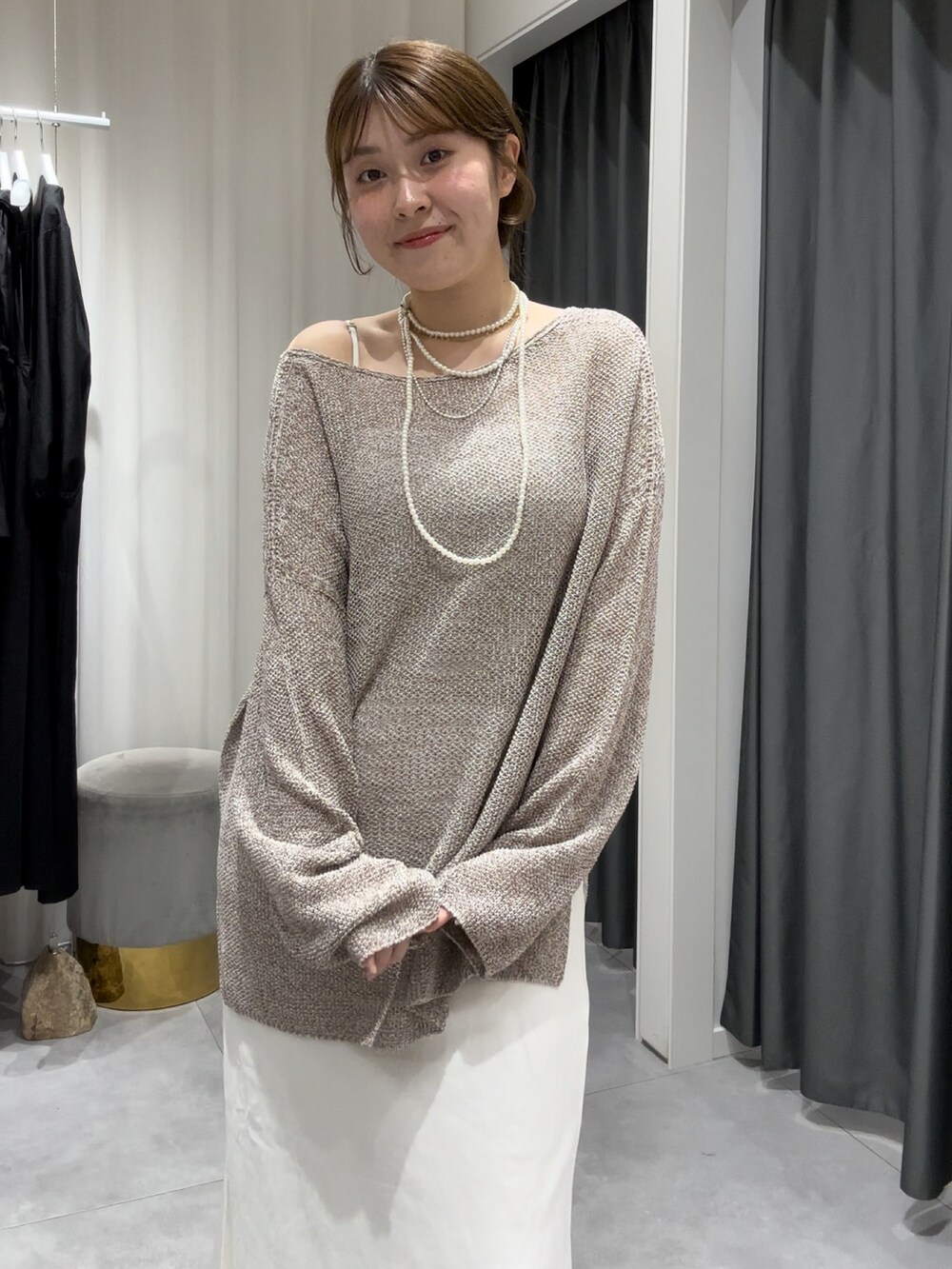 ベージュ系のニット/セーター、ホワイト系のスカート、シルバー系のネックレスを着用したレディースの夏コーディネートの6枚目の写真