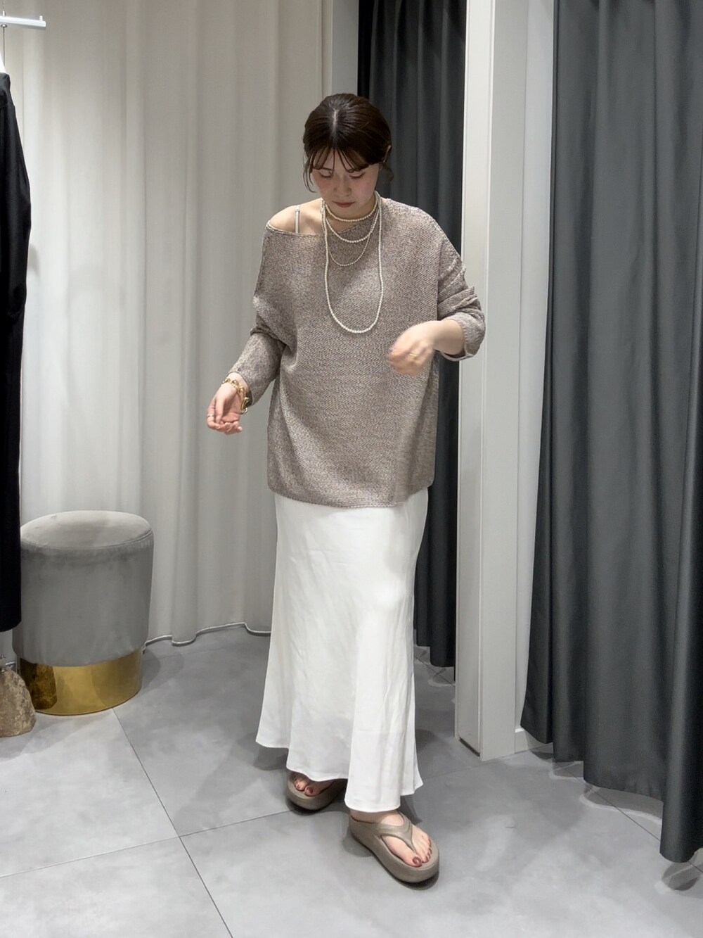 ベージュ系のニット/セーター、ホワイト系のスカート、シルバー系のネックレスを着用したレディースの夏コーディネートの3枚目の写真
