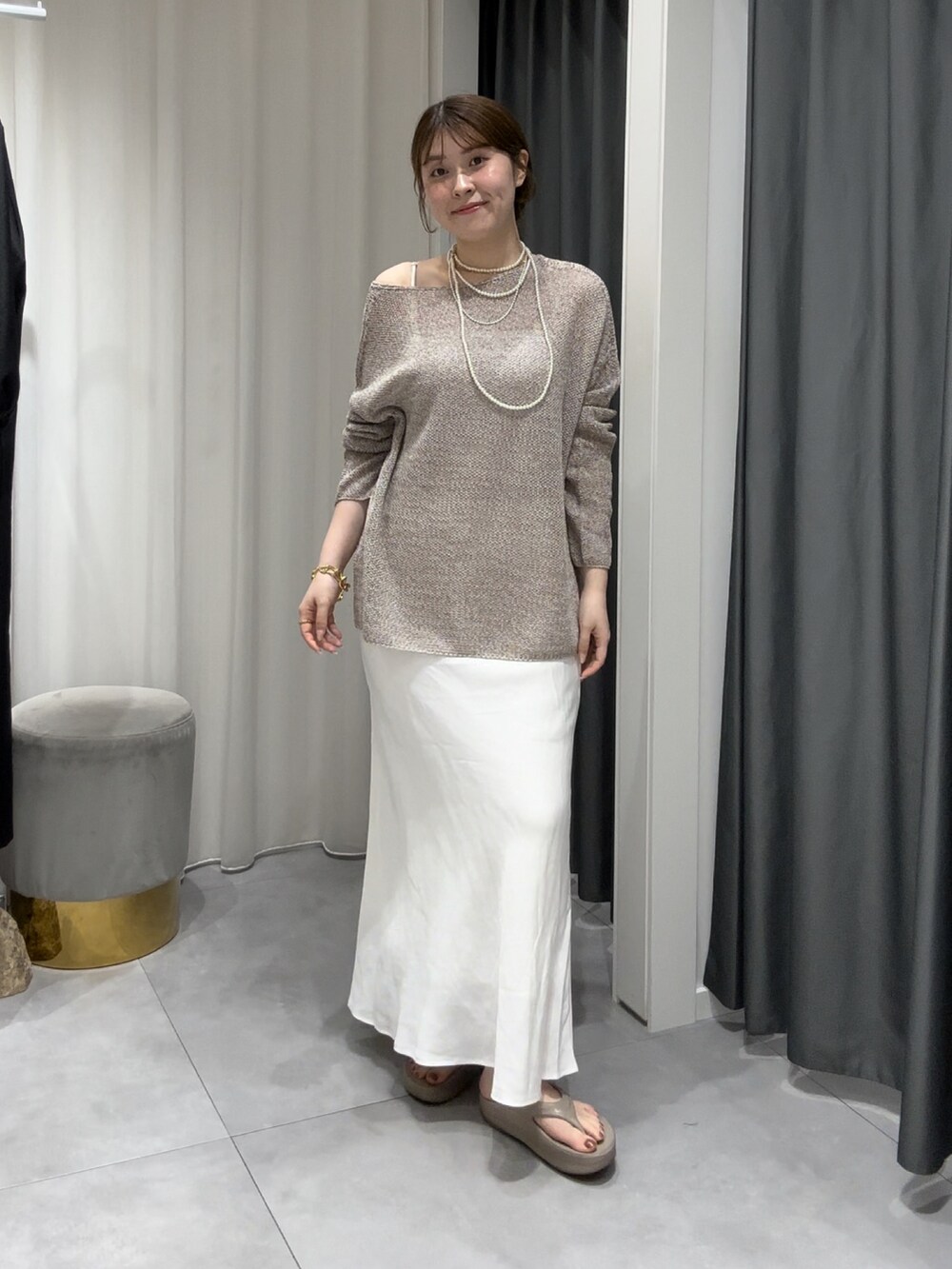 ベージュ系のニット/セーター、ホワイト系のスカート、シルバー系のネックレスを着用したレディースの夏コーディネートの5枚目の写真