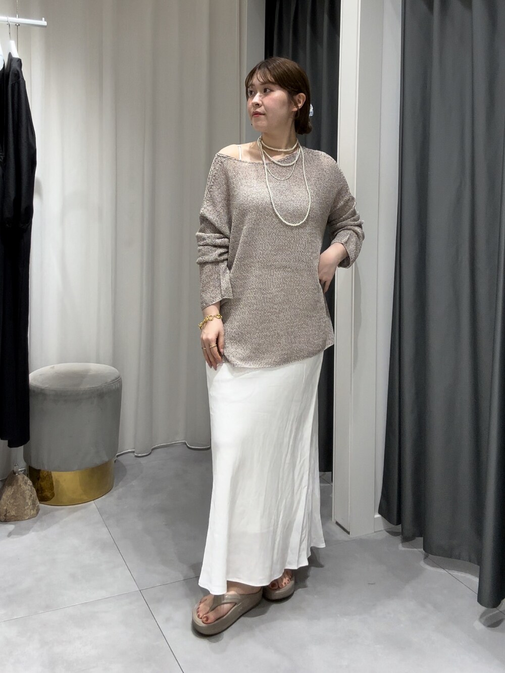 ベージュ系のニット/セーター、ホワイト系のスカート、シルバー系のネックレスを着用したレディースの夏コーディネートの2枚目の写真