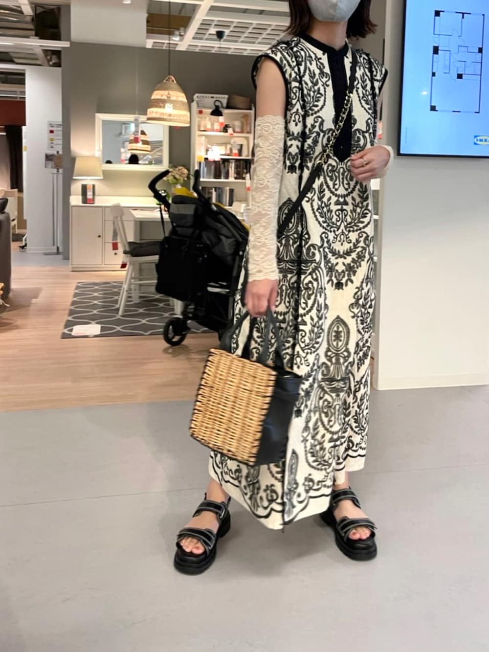 ブラック系のかごバッグ、ホワイト系のワンピース、ブラック系のサンダルを着用したレディースの夏コーディネートの2枚目の写真