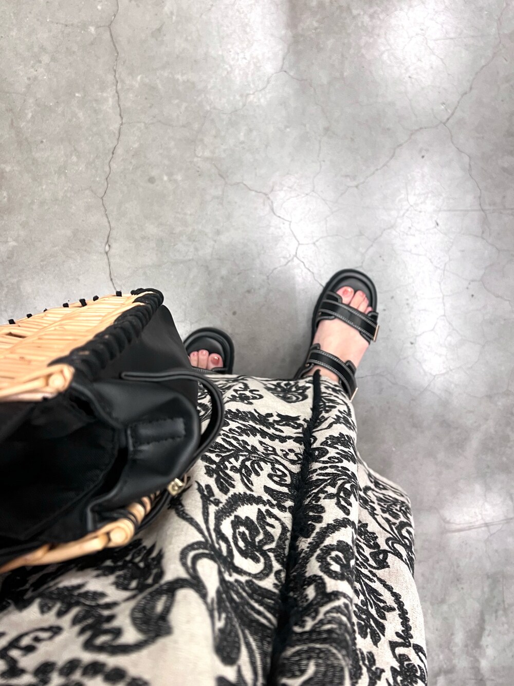 ブラック系のかごバッグ、ホワイト系のワンピース、ブラック系のサンダルを着用したレディースの夏コーディネートの3枚目の写真