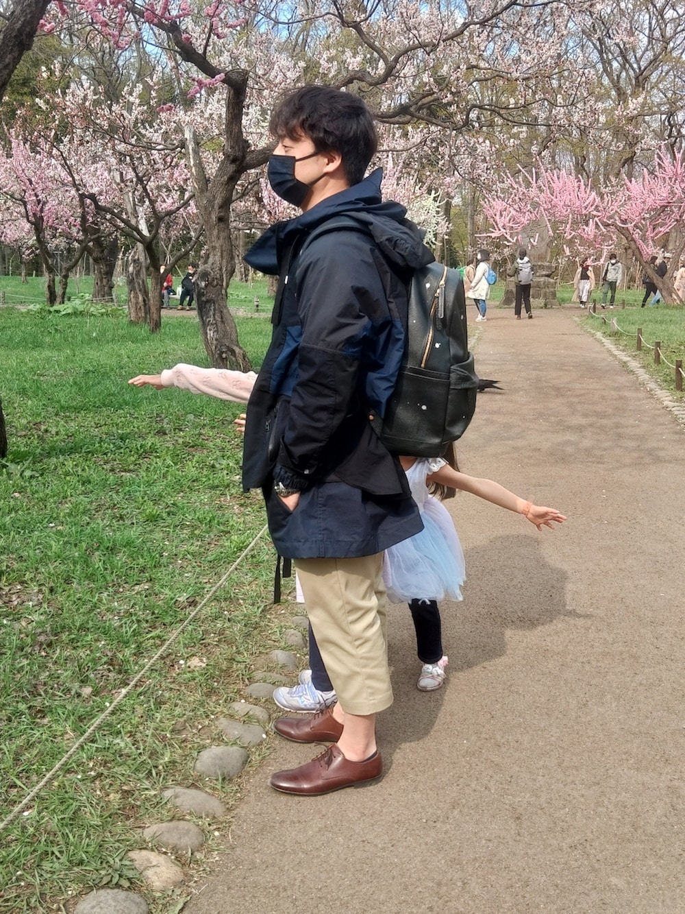 ブラウン系のその他シューズ、ベージュ系のチノパンツ、ブラック系のその他アウターを着用したメンズの春コーディネートの2枚目の写真