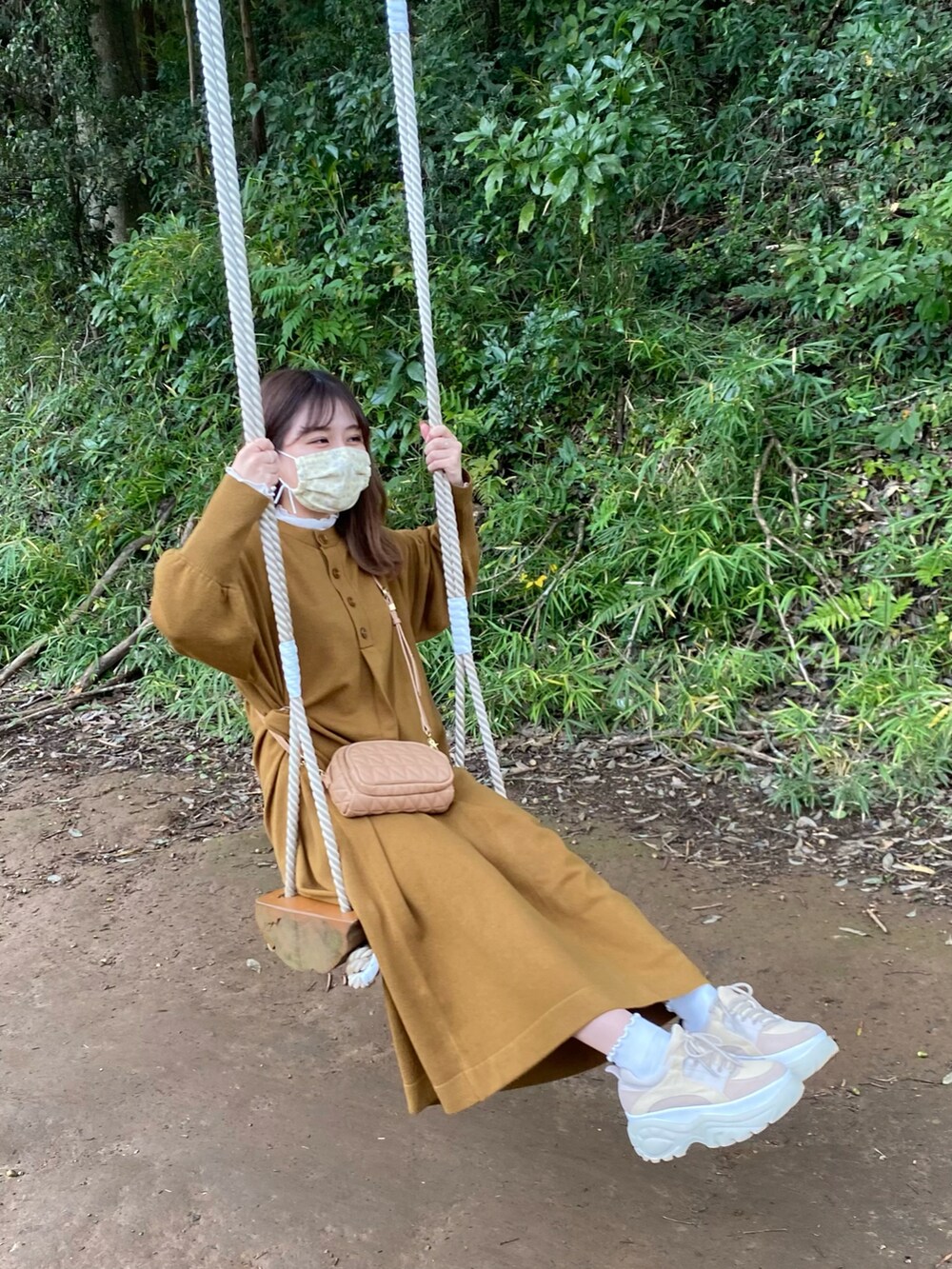 ブラウン系のワンピース、ベージュ系のスニーカー、ホワイト系のTシャツ/カットソーを着用したレディースの秋コーディネートの2枚目の写真