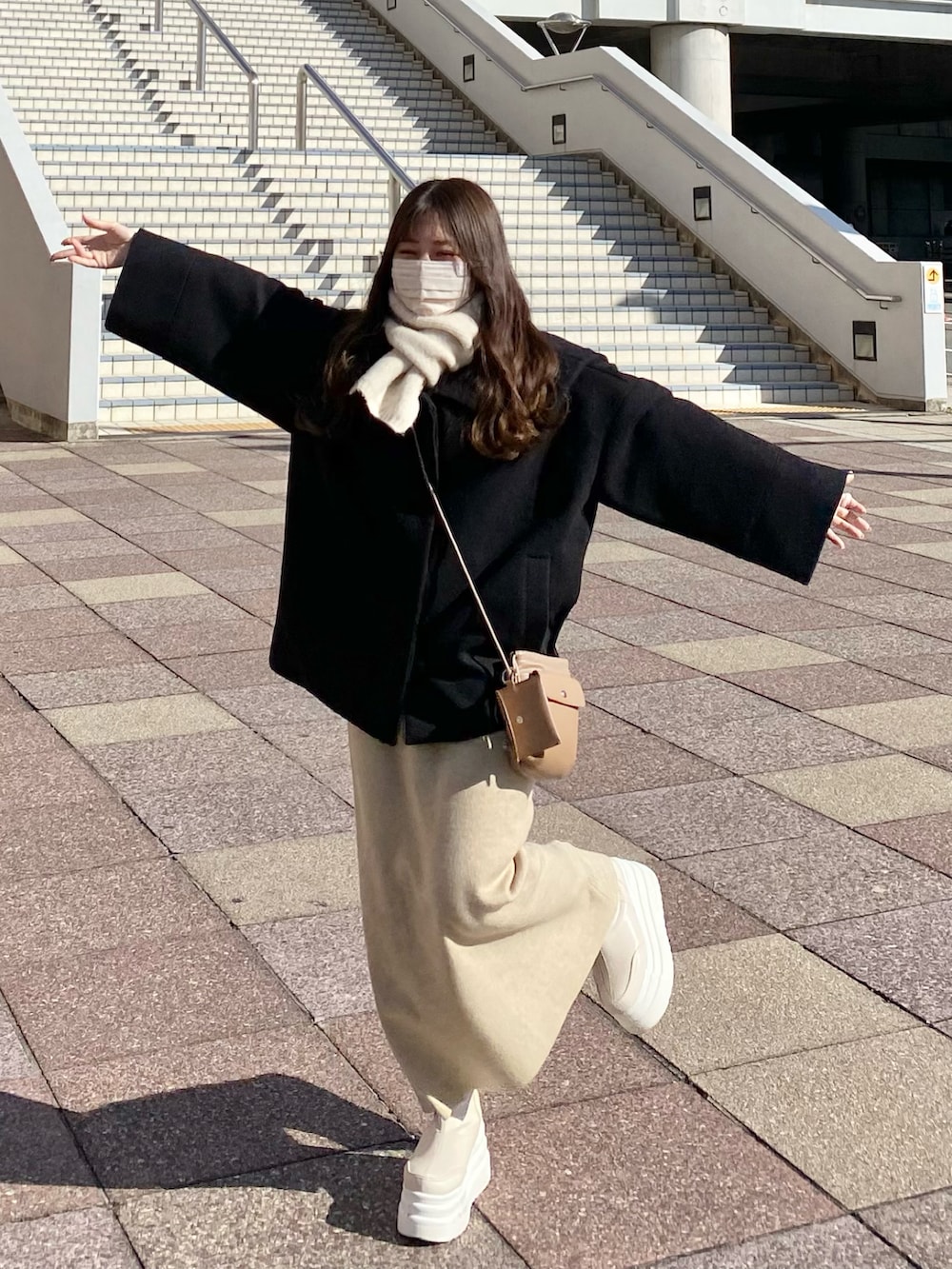 ホワイト系のニット/セーター、ホワイト系のTシャツ/カットソー、ベージュ系のショルダーバッグを着用したレディースの冬コーディネートの3枚目の写真