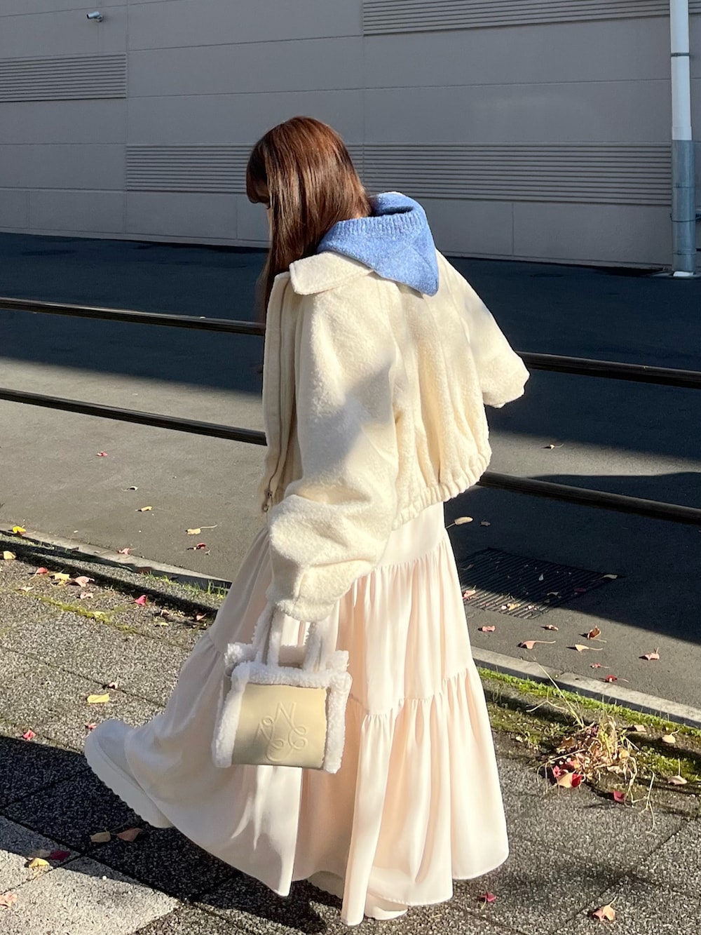 ホワイト系のスカート、ホワイト系のハンドバッグ、ホワイト系のステンカラーコートを着用したレディースの冬コーディネートの2枚目の写真