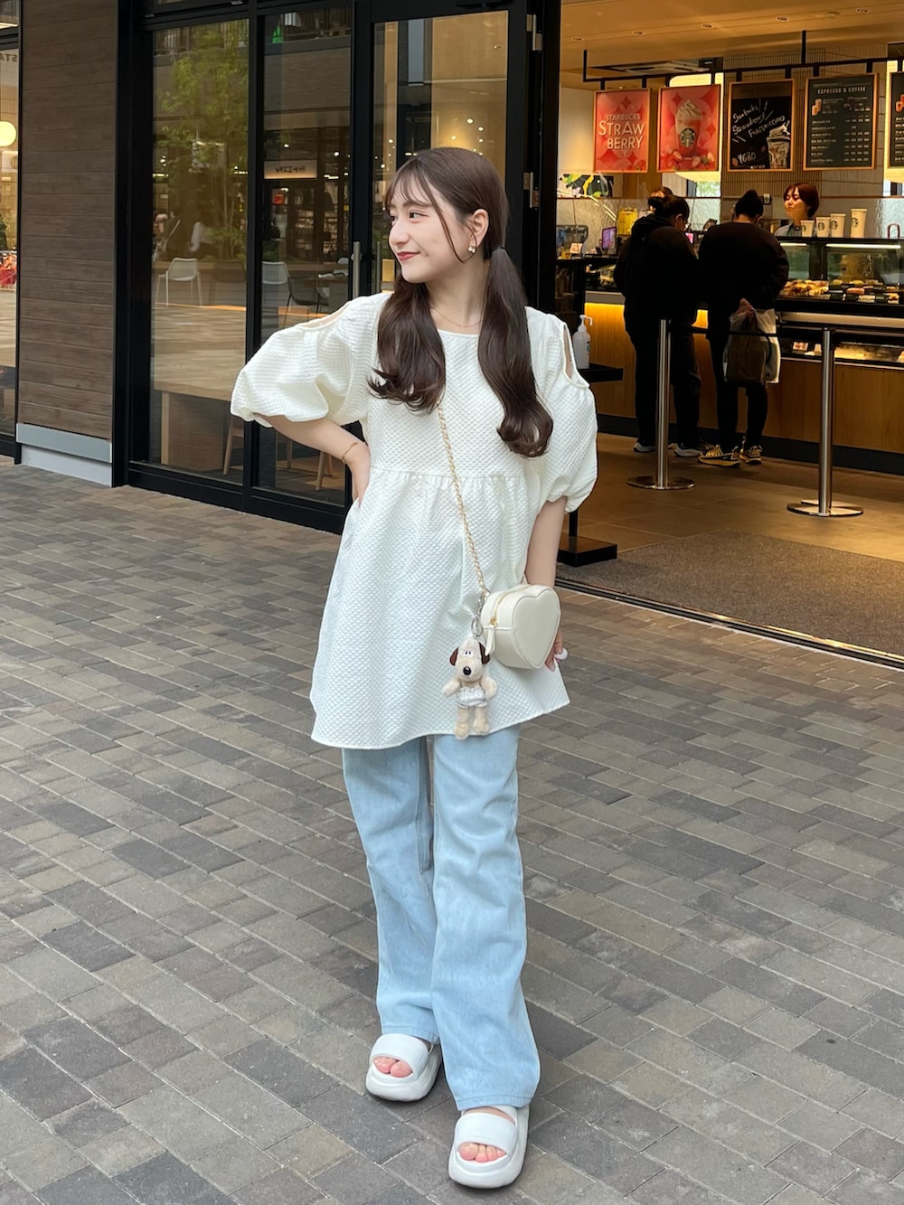 ホワイト系のシャツ/ブラウス、ホワイト系のショルダーバッグ、ブルー系のデニムパンツを着用したレディースの夏コーディネートの2枚目の写真