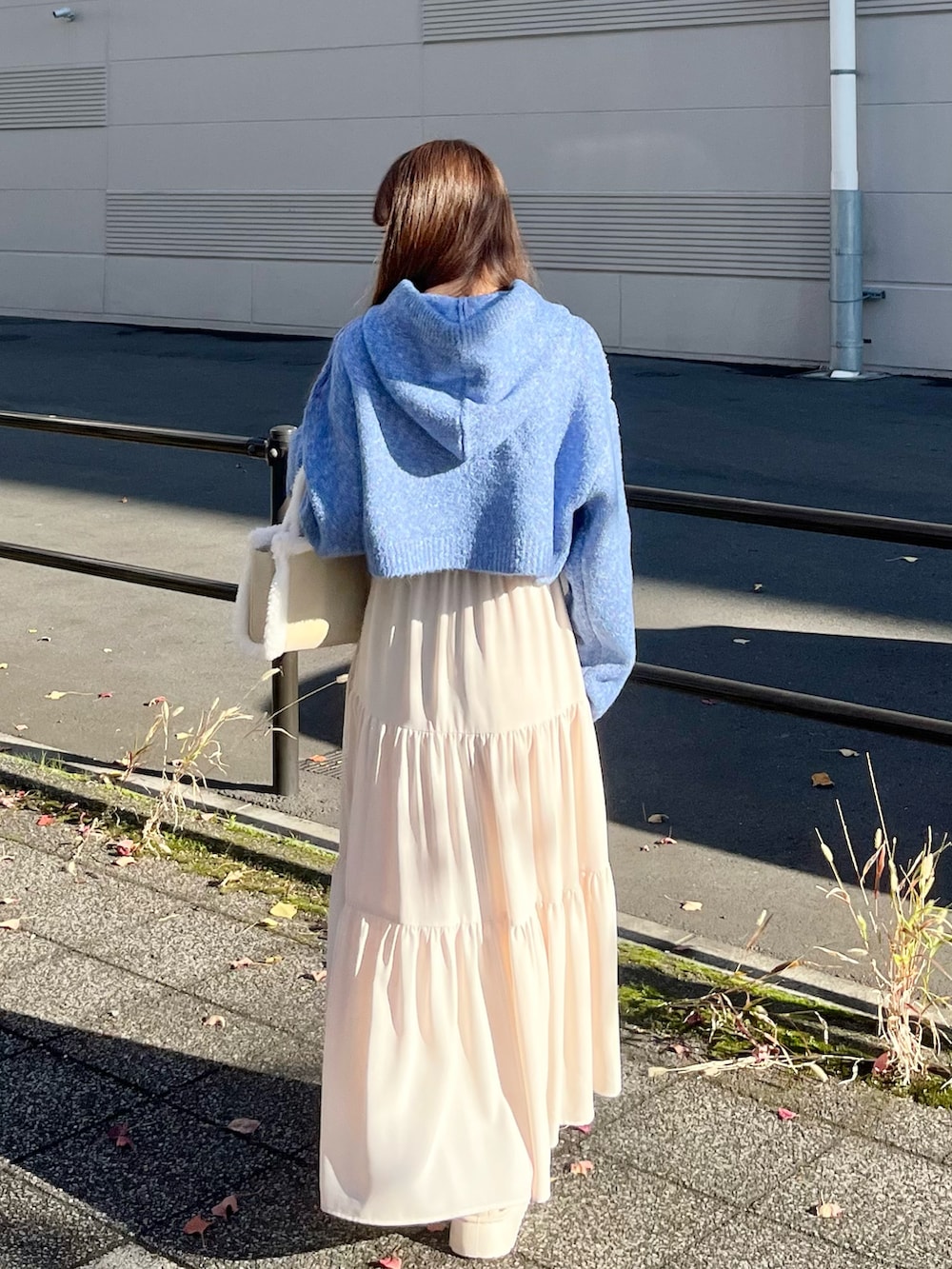 ホワイト系のスカート、ホワイト系のハンドバッグ、ホワイト系のステンカラーコートを着用したレディースの冬コーディネートの4枚目の写真