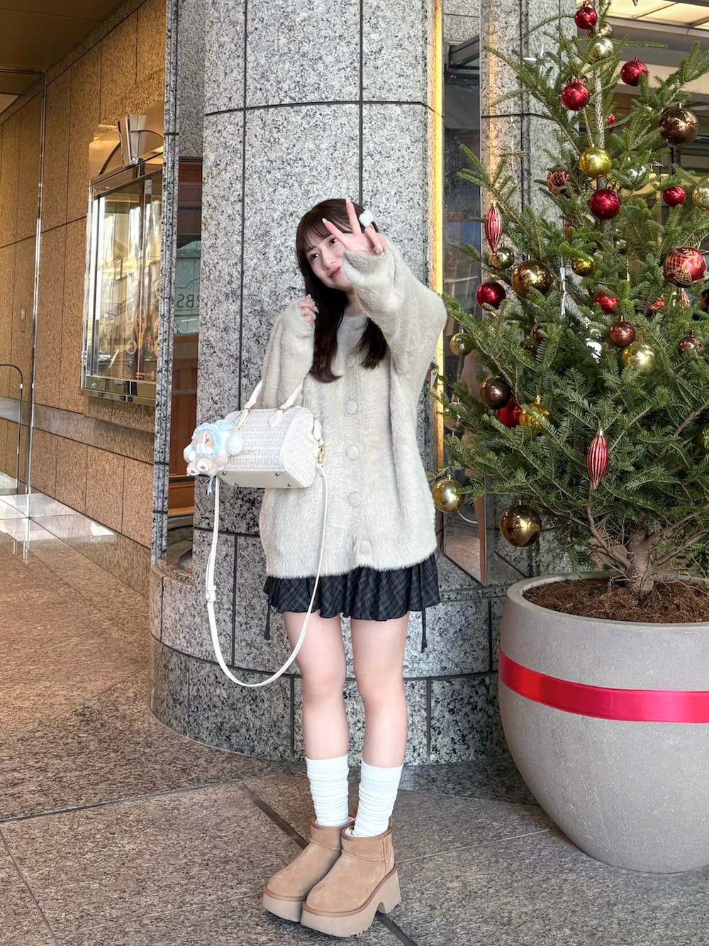 グレー系のカーディガン/ボレロ、ホワイト系のボストンバッグ、ブルー系のスカートを着用したレディースの冬コーディネートの2枚目の写真