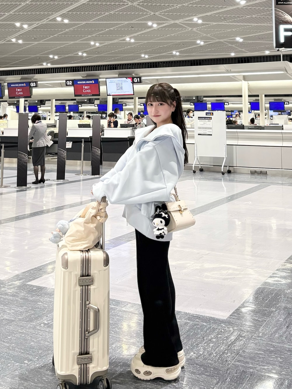 ブルー系のパーカー、ホワイト系のショルダーバッグ、ブラック系のパンツを着用したレディースの春コーディネートの2枚目の写真