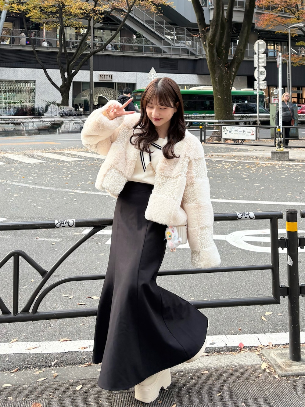 ホワイト系のノーカラージャケット、ホワイト系のバッグ、ブラック系のスカートを着用したレディースの秋コーディネートの2枚目の写真