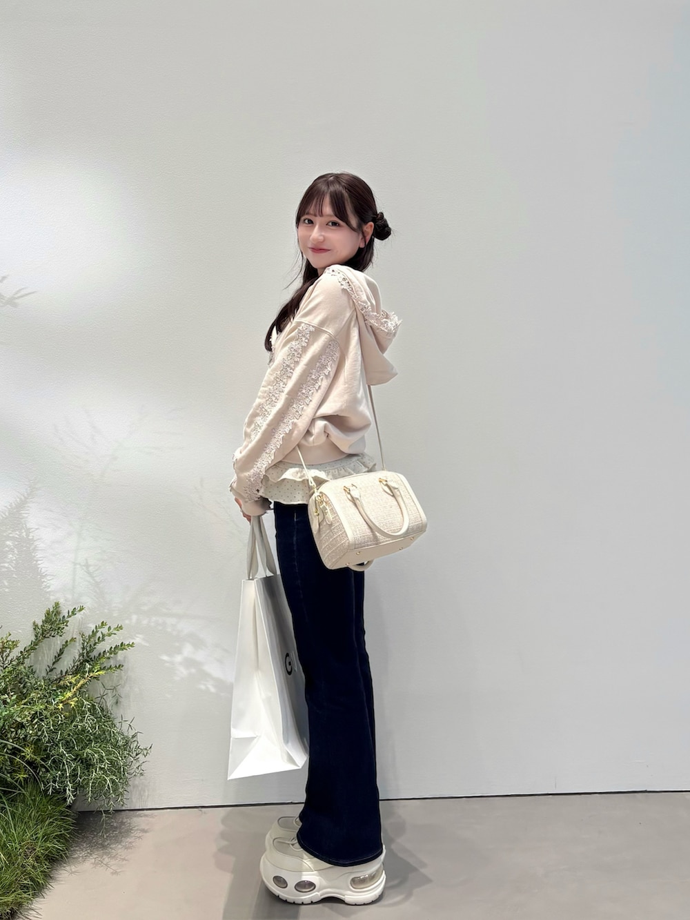 ピンク系のパーカー、ブルー系のデニムパンツ、ホワイト系のスニーカーを着用したレディースの秋コーディネートの2枚目の写真