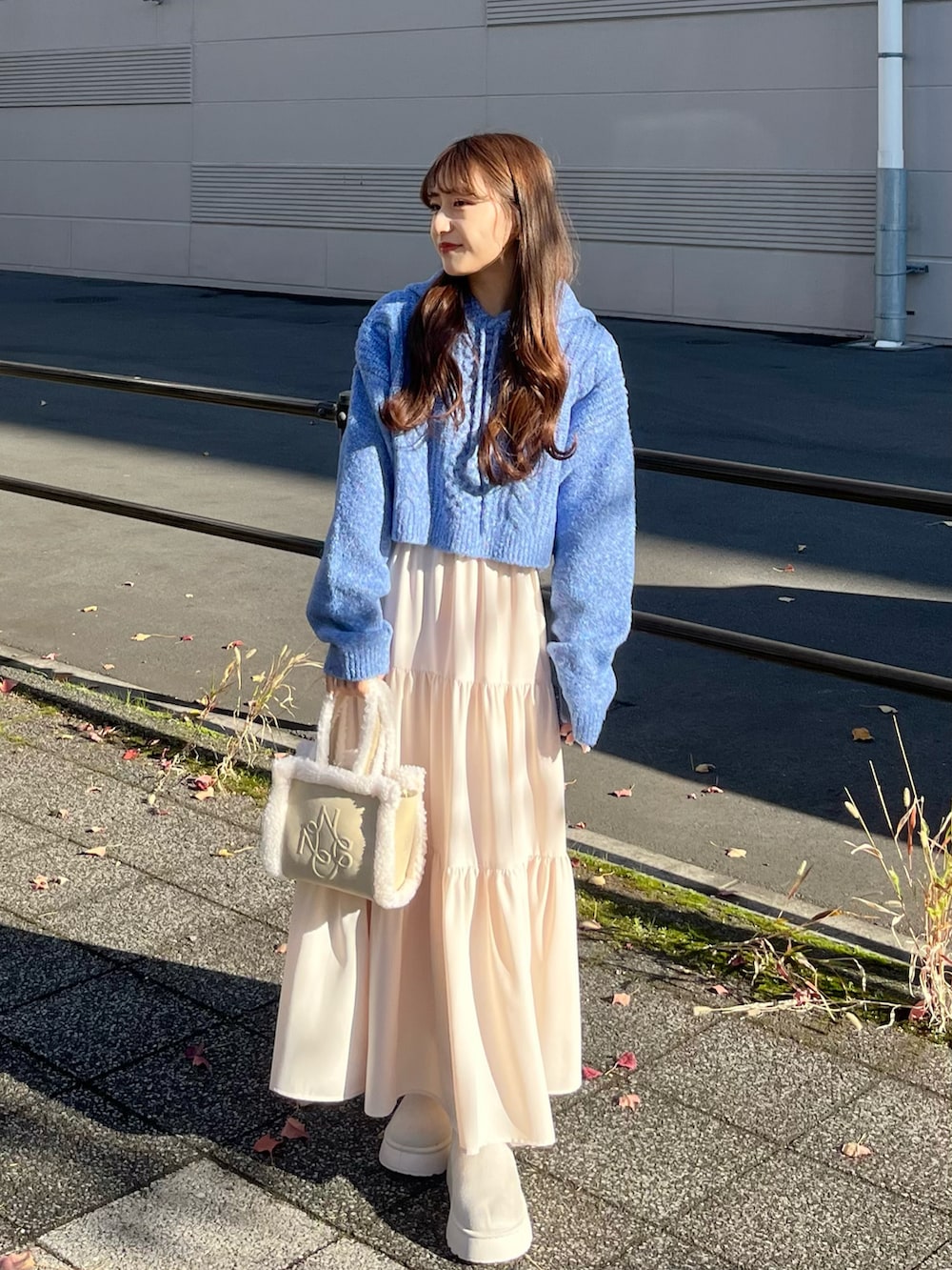 ホワイト系のスカート、ホワイト系のハンドバッグ、ホワイト系のステンカラーコートを着用したレディースの冬コーディネートの3枚目の写真