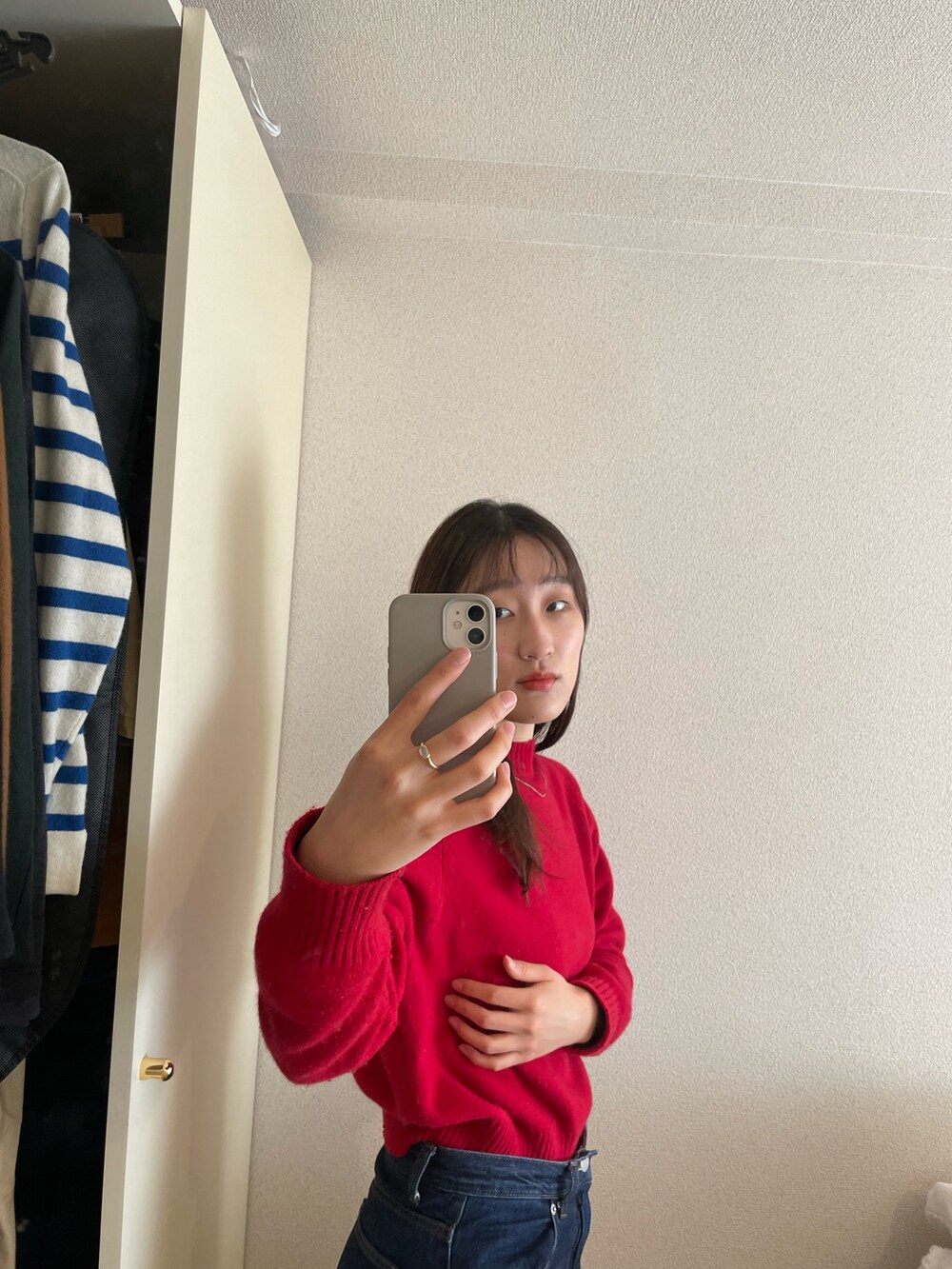 レッド系のニット/セーター、ブラック系のデニムパンツを着用したレディースの冬コーディネートの2枚目の写真