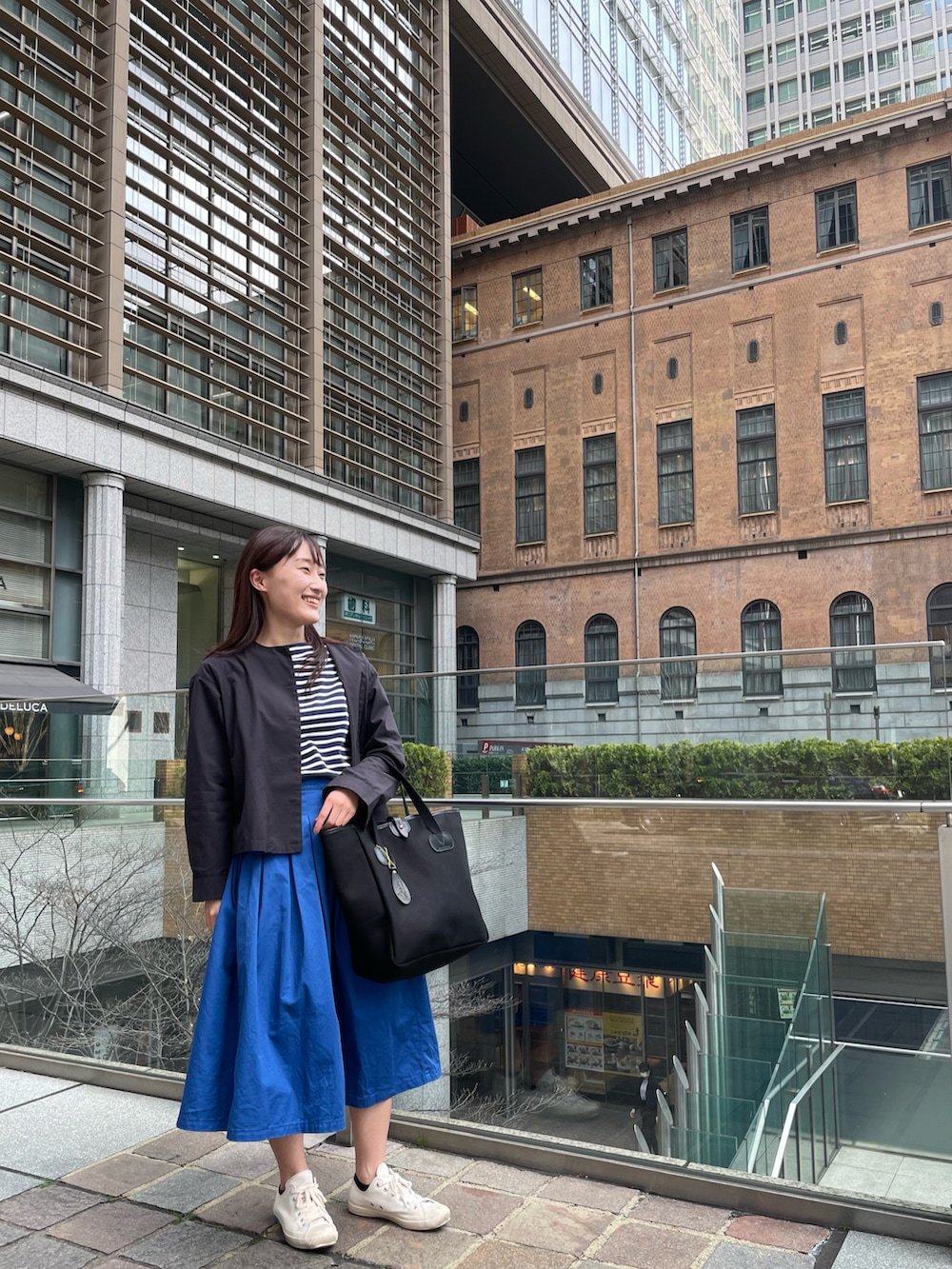 ブルー系のスカート、ブルー系のTシャツ/カットソー、ブラック系のトートバッグを着用したレディースの春コーディネートの2枚目の写真