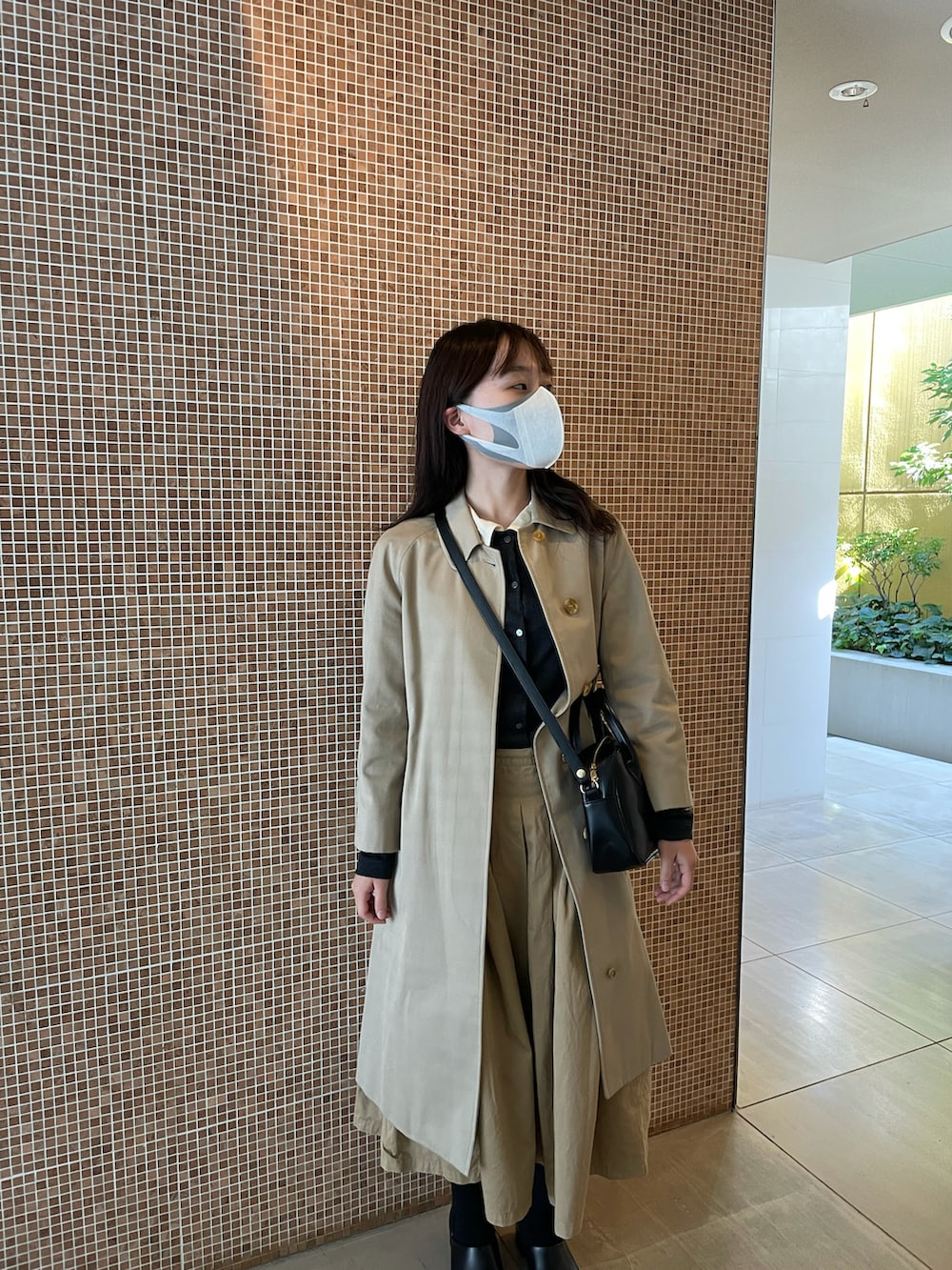 ブラック系のトップス、ブラック系のショルダーバッグ、ベージュ系のジャケット/アウターを着用したレディースの秋コーディネートの2枚目の写真