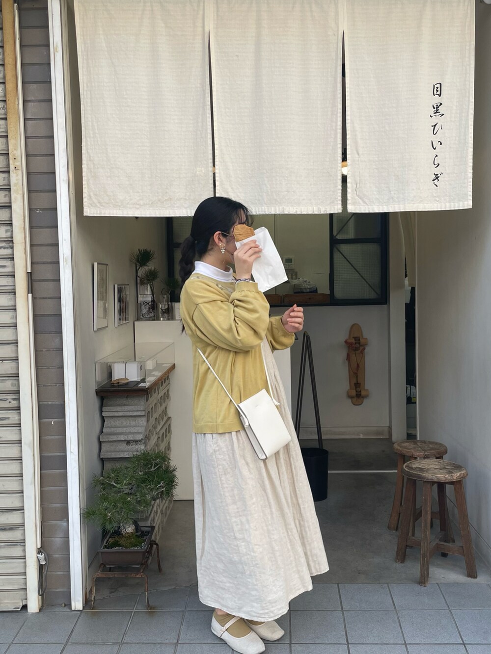 イエロー系のニット/セーター、ベージュ系のワンピース/ドレスを着用したレディースの春コーディネートの2枚目の写真