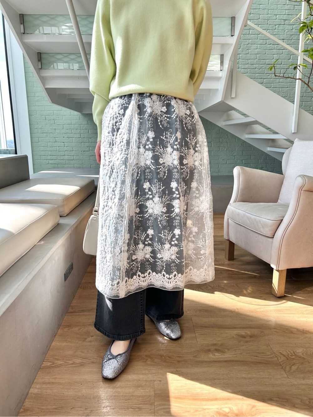 ブラック系のデニムパンツ、ホワイト系のショルダーバッグ、シルバー系のパンプスを着用したレディースの春コーディネートの5枚目の写真